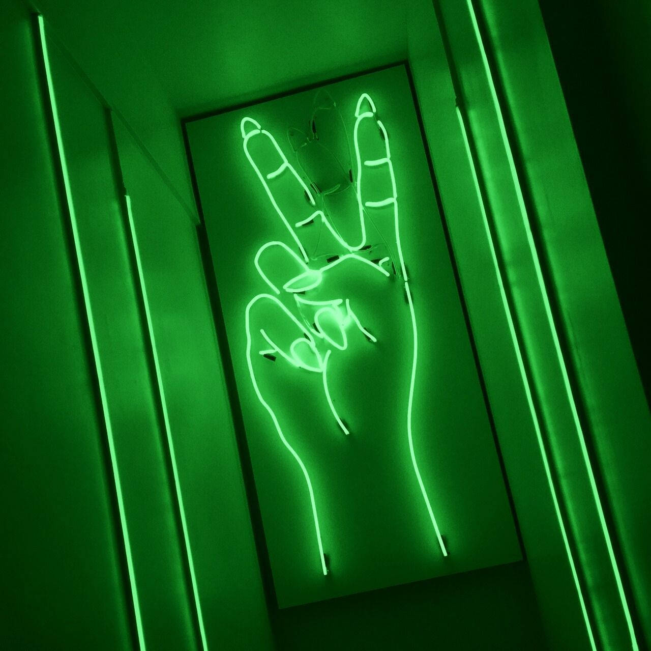 Peace 桌布 壁紙 — 一個發光的綠色霓虹燈牌，形狀像一隻手做出和平手勢，掛在由垂直霓虹燈條框住的牆上。
