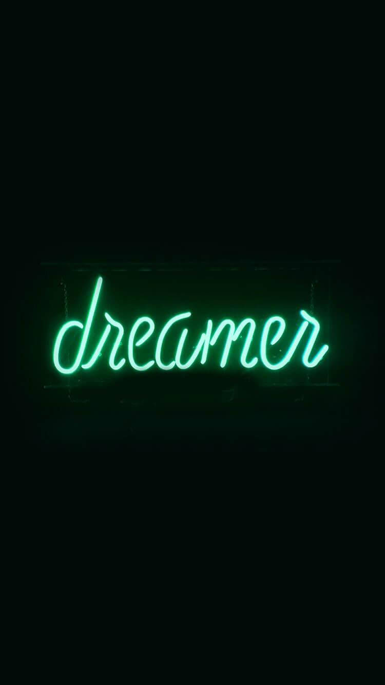 黑色美學手機 桌布 壁紙 — 一個發光的綠色霓虹燈牌，拼出dreamer，在漆黑的背景下明亮地閃耀。