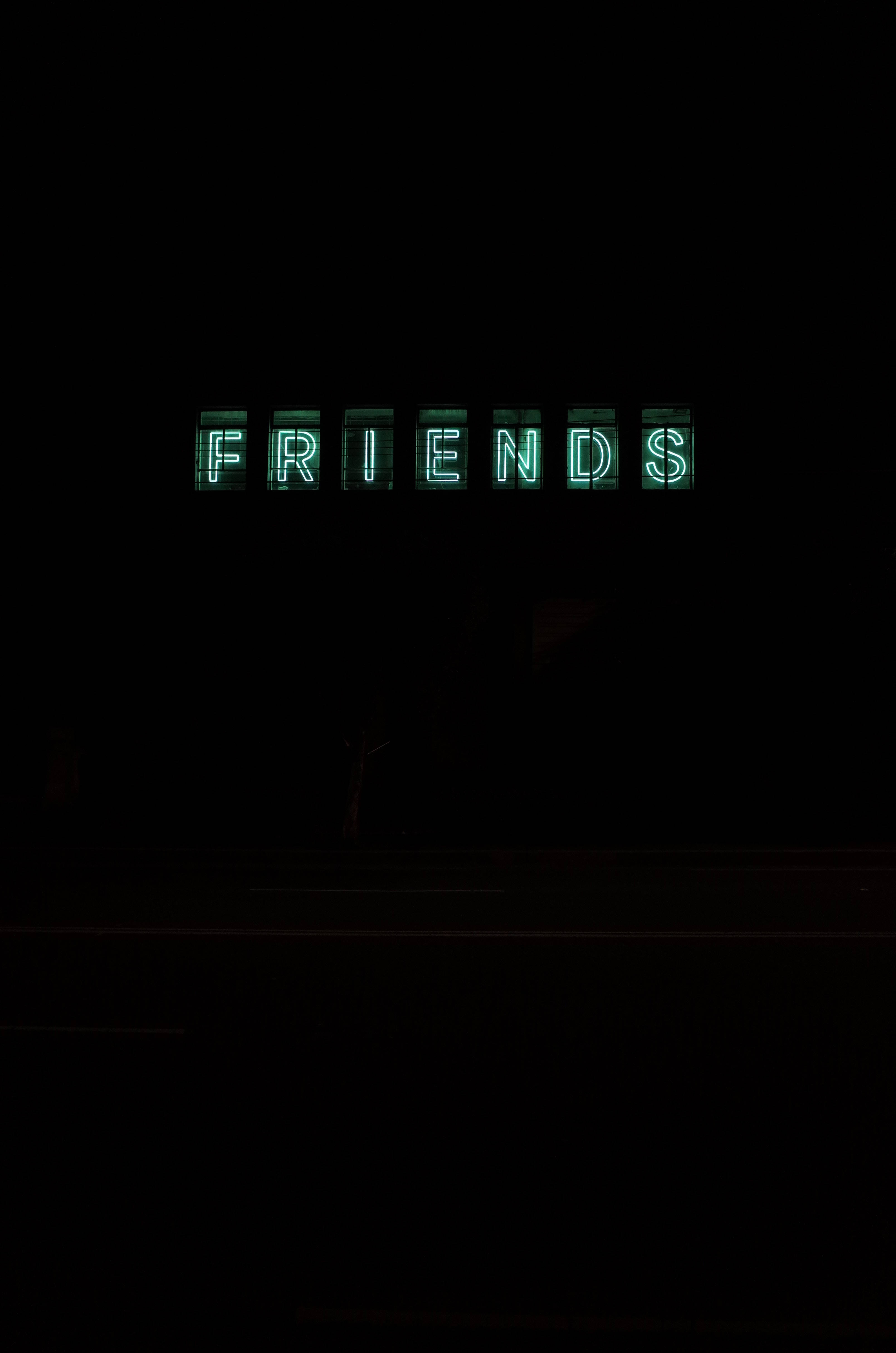 老友記 桌布 壁紙 — 一個發光的綠色霓虹燈牌，拼寫出 FRIENDS，照亮了漆黑的夜晚場景。