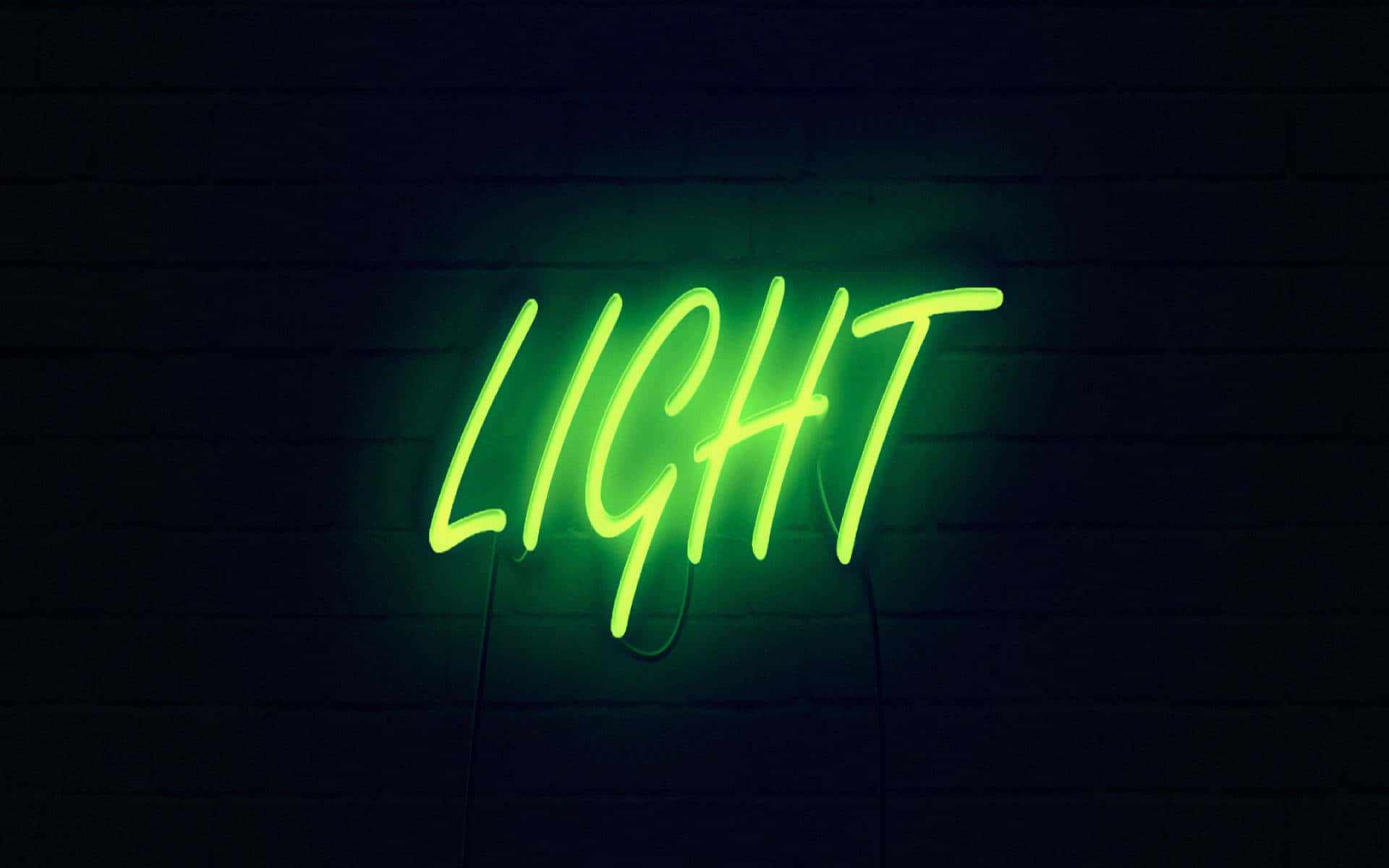 霓虹綠美學 桌布 壁紙 — 一個發光的綠色霓虹燈牌，拼寫著「LIGHT」，在昏暗的環境中對著深色磚牆投射出鮮豔的光芒。