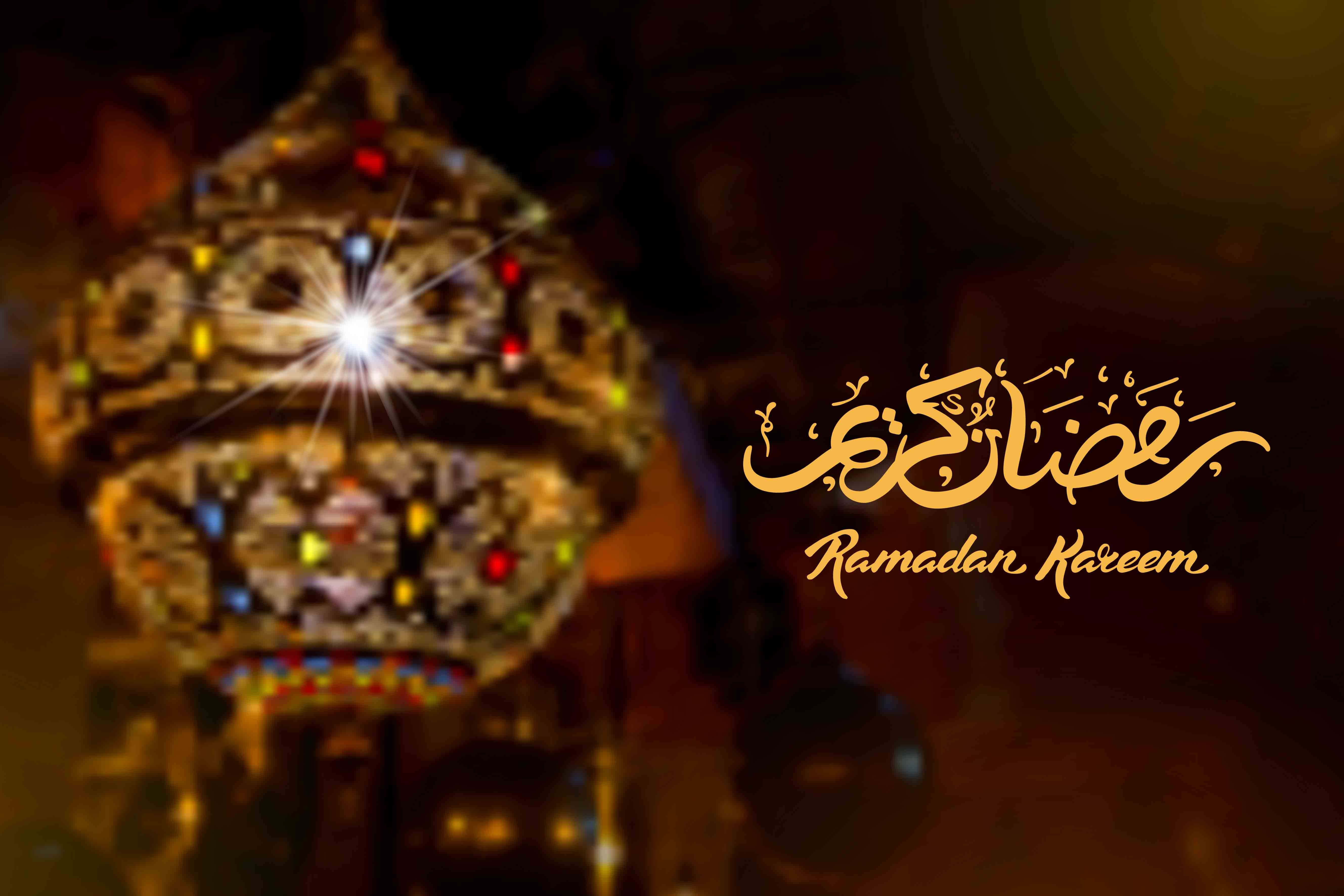 Ramadan Kareem 桌布 壁紙 — 一個發光的華麗燈籠，帶有彩色燈光，在黑暗背景上閃耀，並配有優雅的金色 Ramadan Kareem 書法。