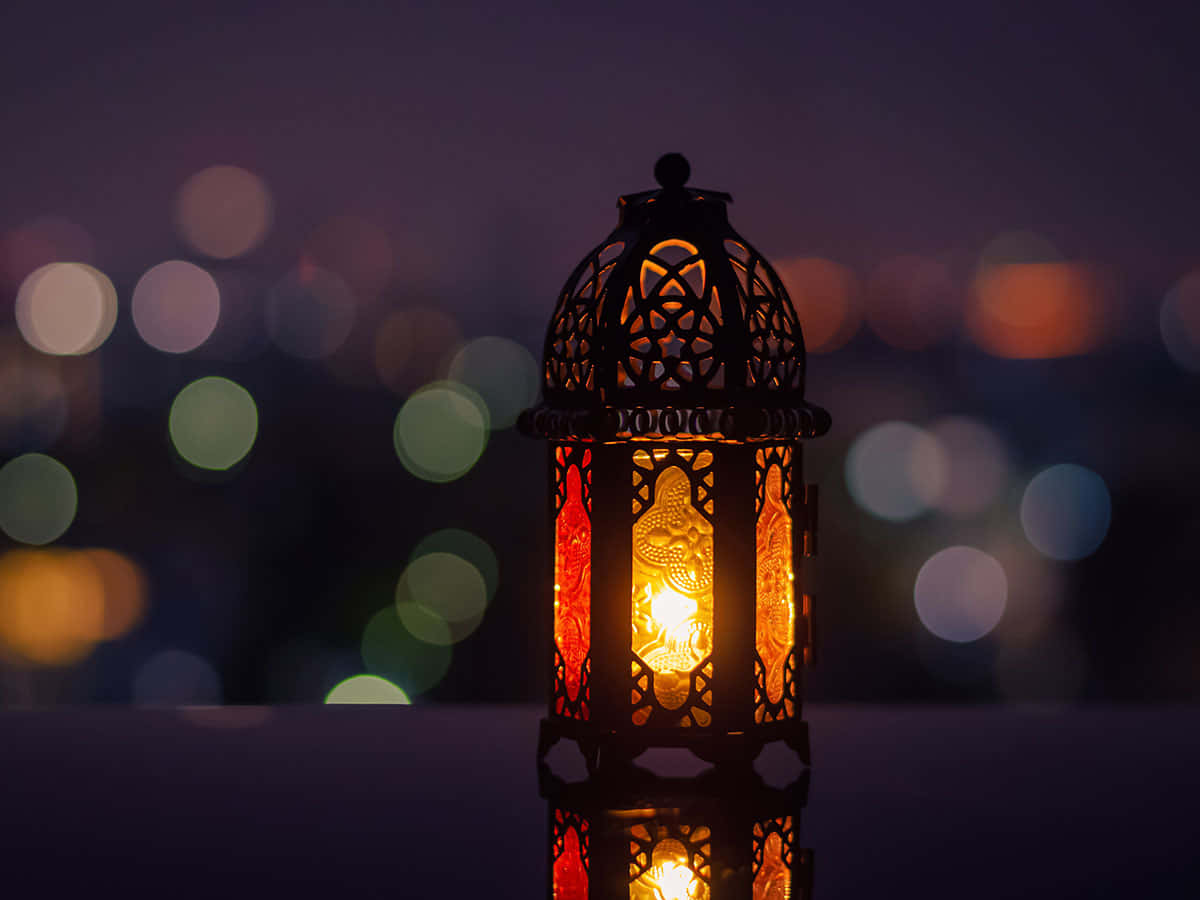 Lantern 桌布 壁紙 — 一個發光的華麗燈籠，帶有精緻的鏤空圖案，在夜晚模糊的城市景觀中投射出溫暖的光芒。