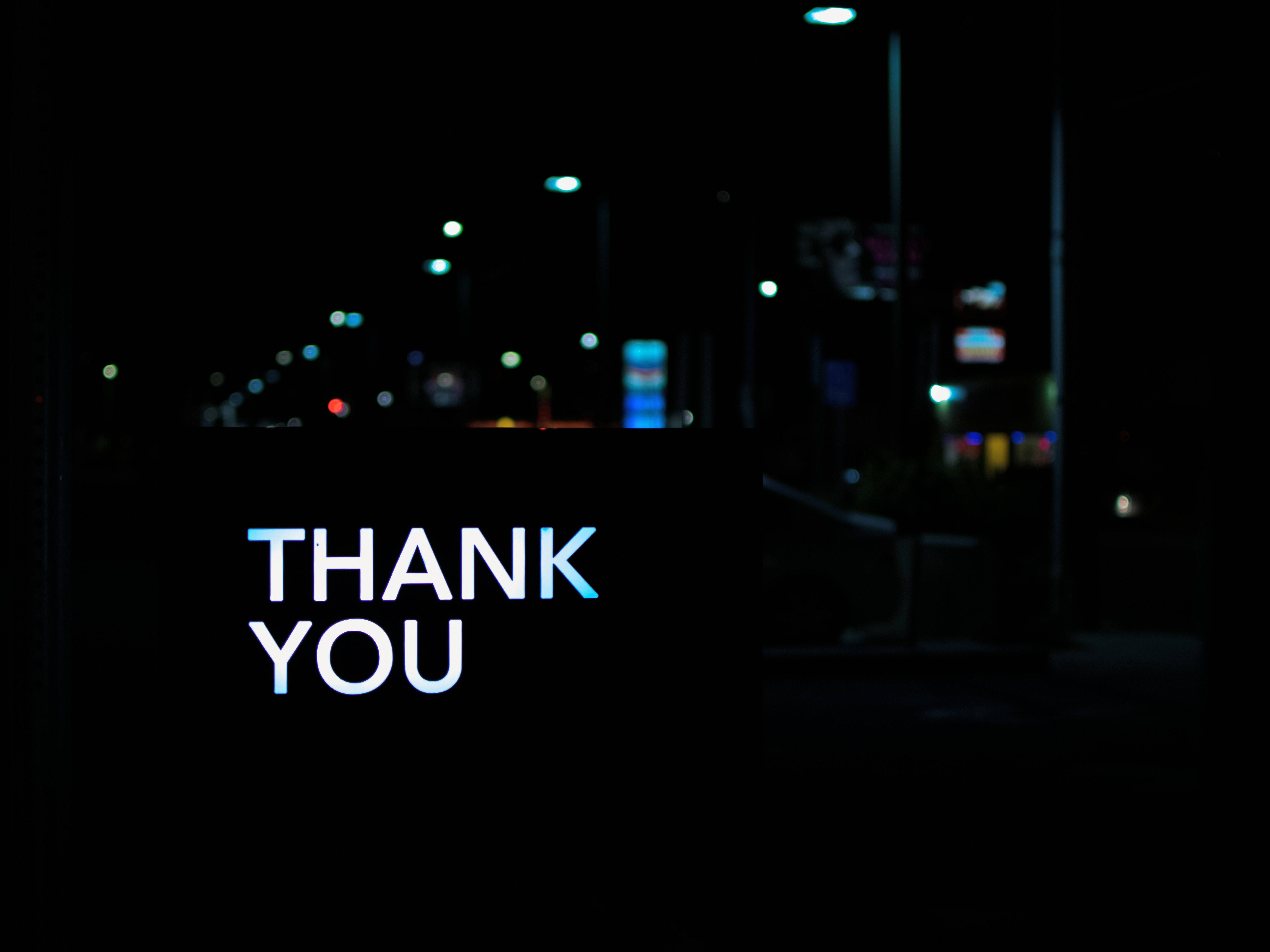 Thank 桌布 壁紙 — 一個發光的藍白色「THANK YOU」標誌在黑暗的夜晚街道上顯得格外突出，背景是模糊的城市燈光。