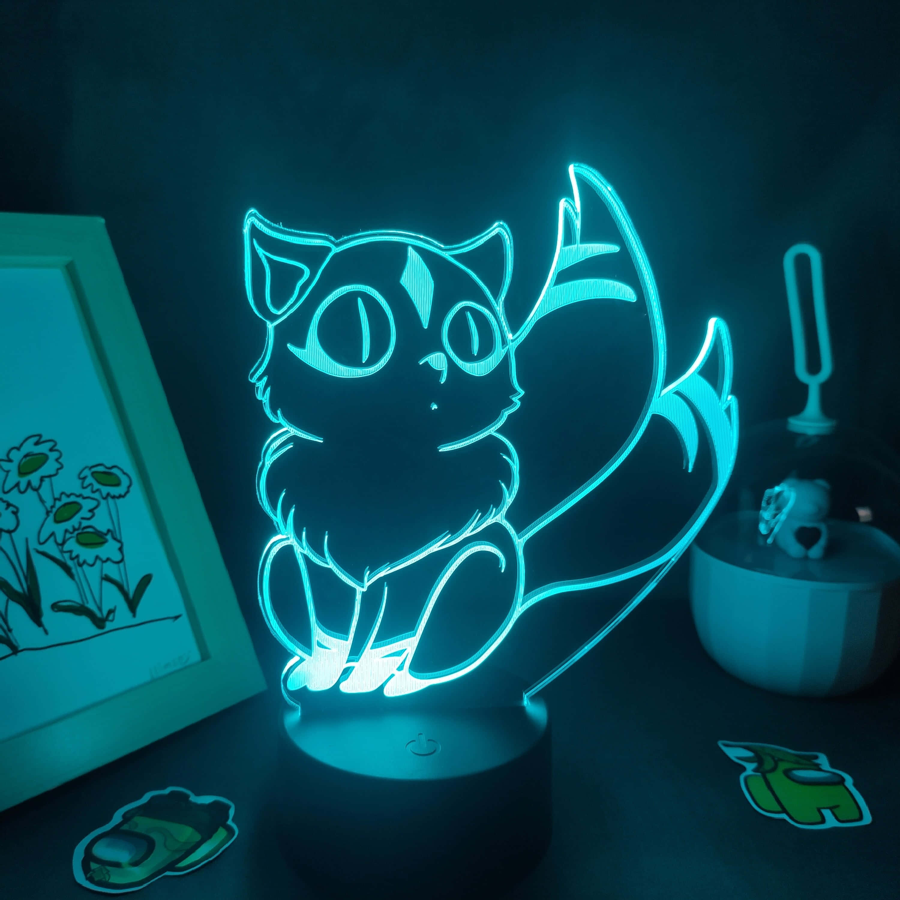 Inuyasha Nekomata 桌布 壁紙 — 一個發光的藍色3D貓燈照亮了黑暗的書桌，旁邊有裱框畫作和遊戲貼紙。