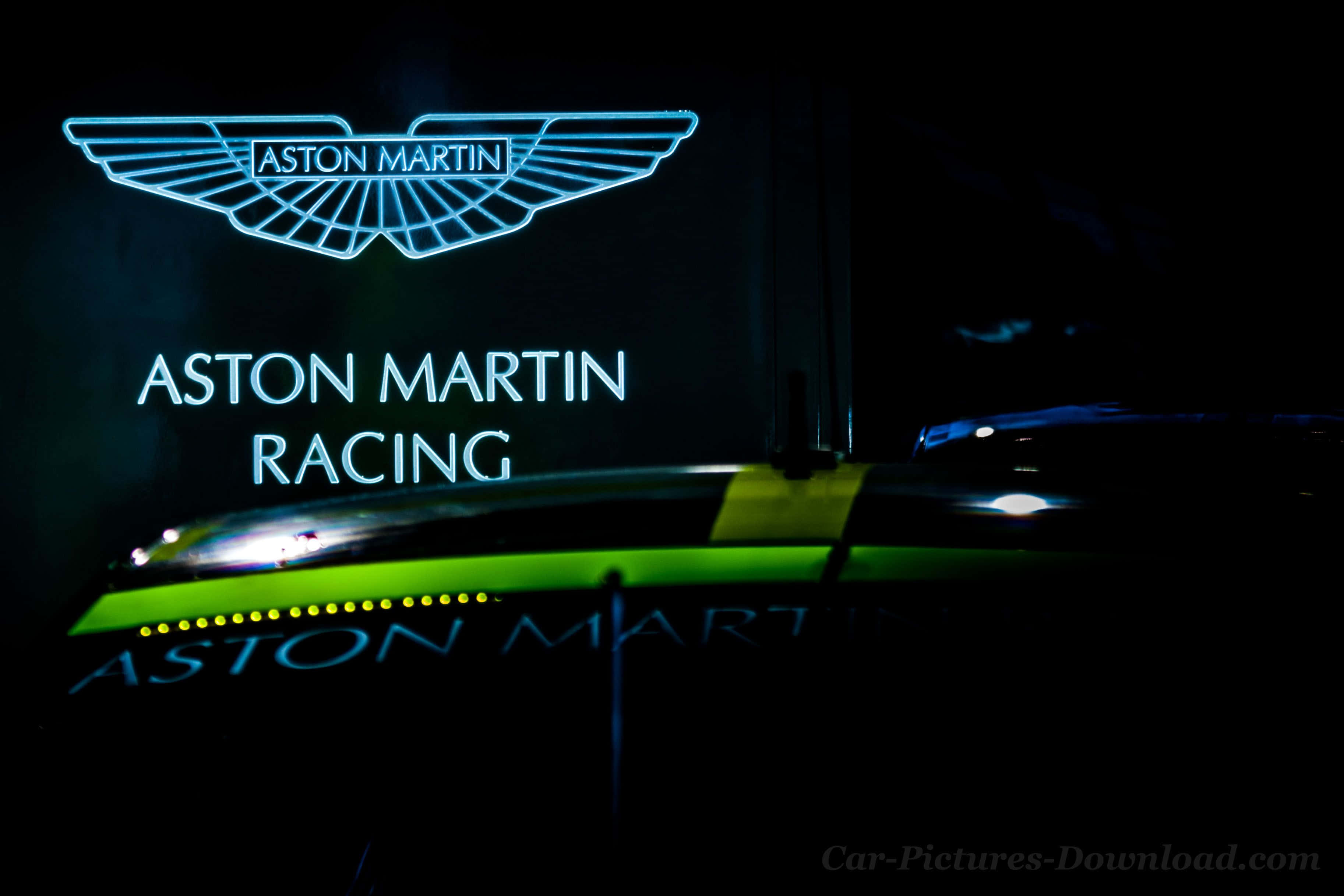 奧斯頓馬丁 桌布 壁紙 — 一個發光的藍色Aston Martin Racing霓虹燈牌在夜晚照亮了一輛時尚的綠色賽車。