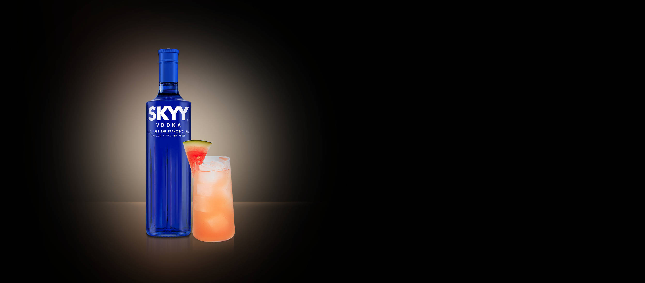 alcohol 桌布 壁紙 — 一個發光的藍色Skyy Vodka酒瓶，旁邊放著一杯充滿活力的粉紅色雞尾酒，飾以萊姆角，背景為黑暗的聚光燈效果。