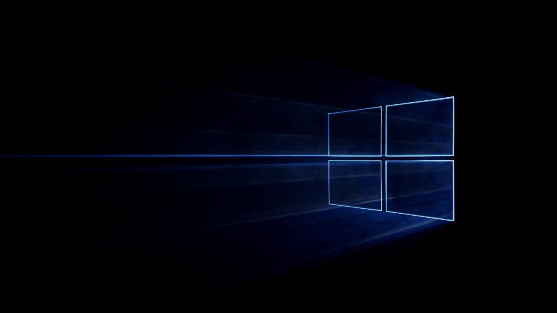 黑色 Windows 10 桌布 壁紙 — 一個發光的藍色Windows標誌從黑暗中浮現，光線穿過其窗格。