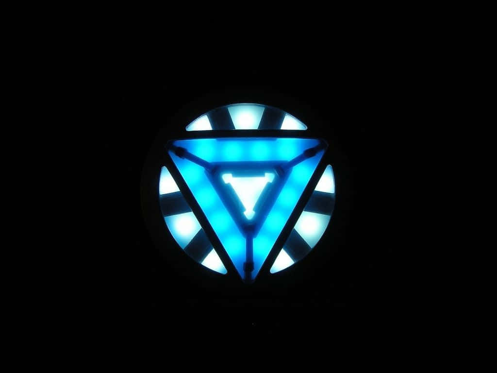 Iron Man Arc Reactor 桌布 壁紙 — 一個發光的藍色三角形弧形反應器在漆黑的背景下脈動著光芒。