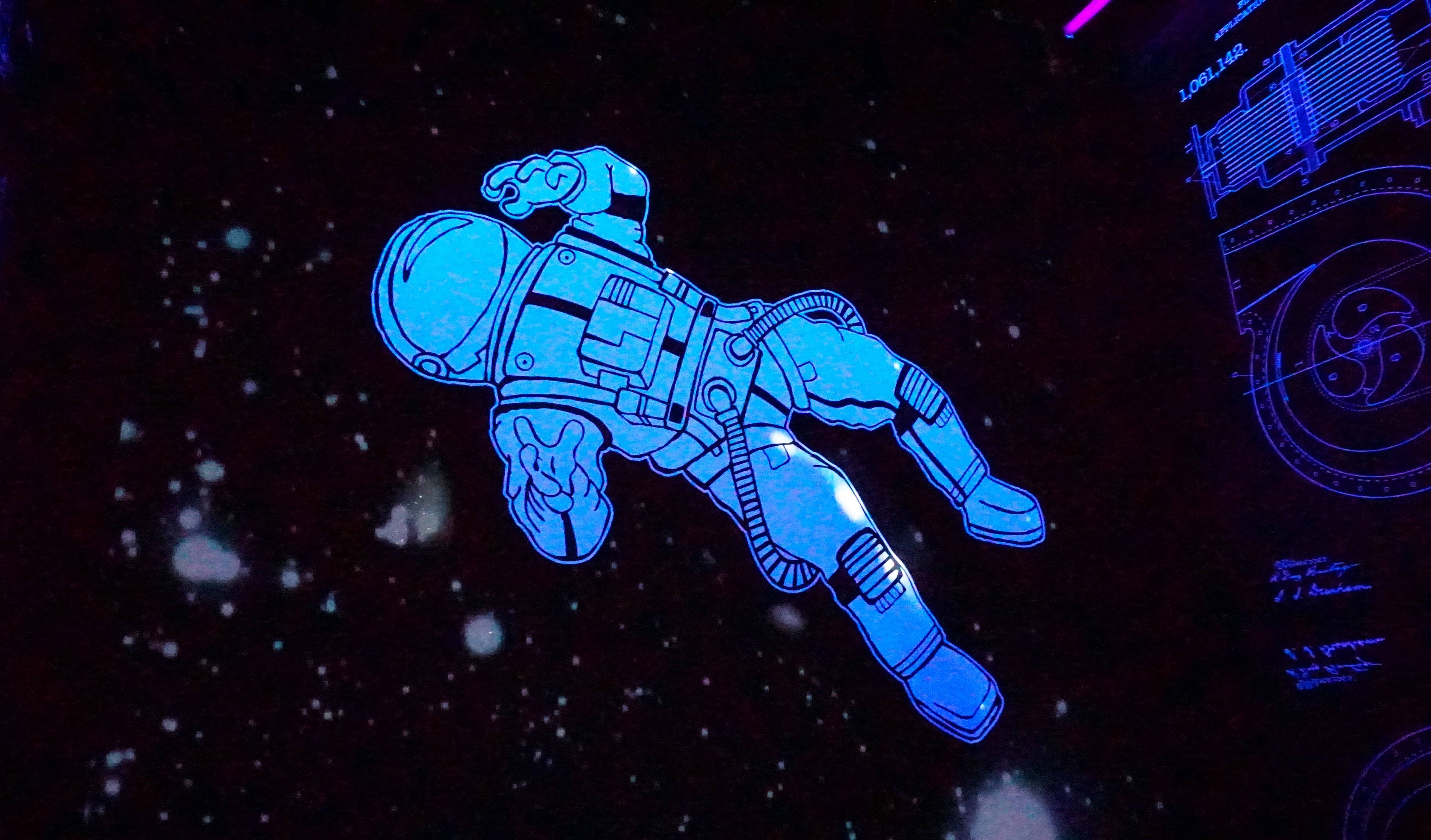 動態桌面 桌布 壁紙 — 一個發光的藍色太空人在星空黑色背景中漂浮，右側有未來感的藍色示意圖。