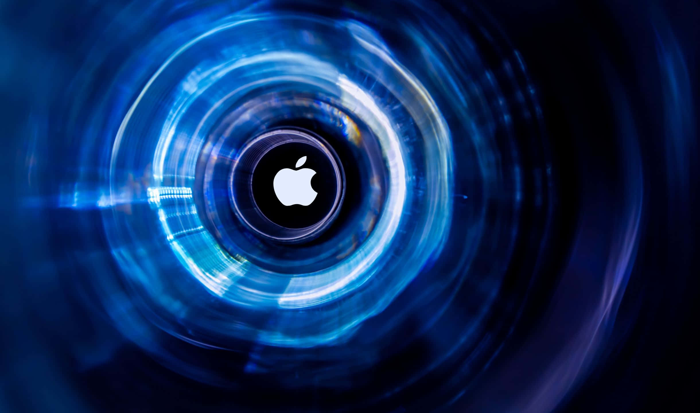 2440x1440 Apple 桌布 壁紙 — 一個發光的藍色數位隧道向內螺旋，在深色背景上顯現出一個置中的Apple標誌。
