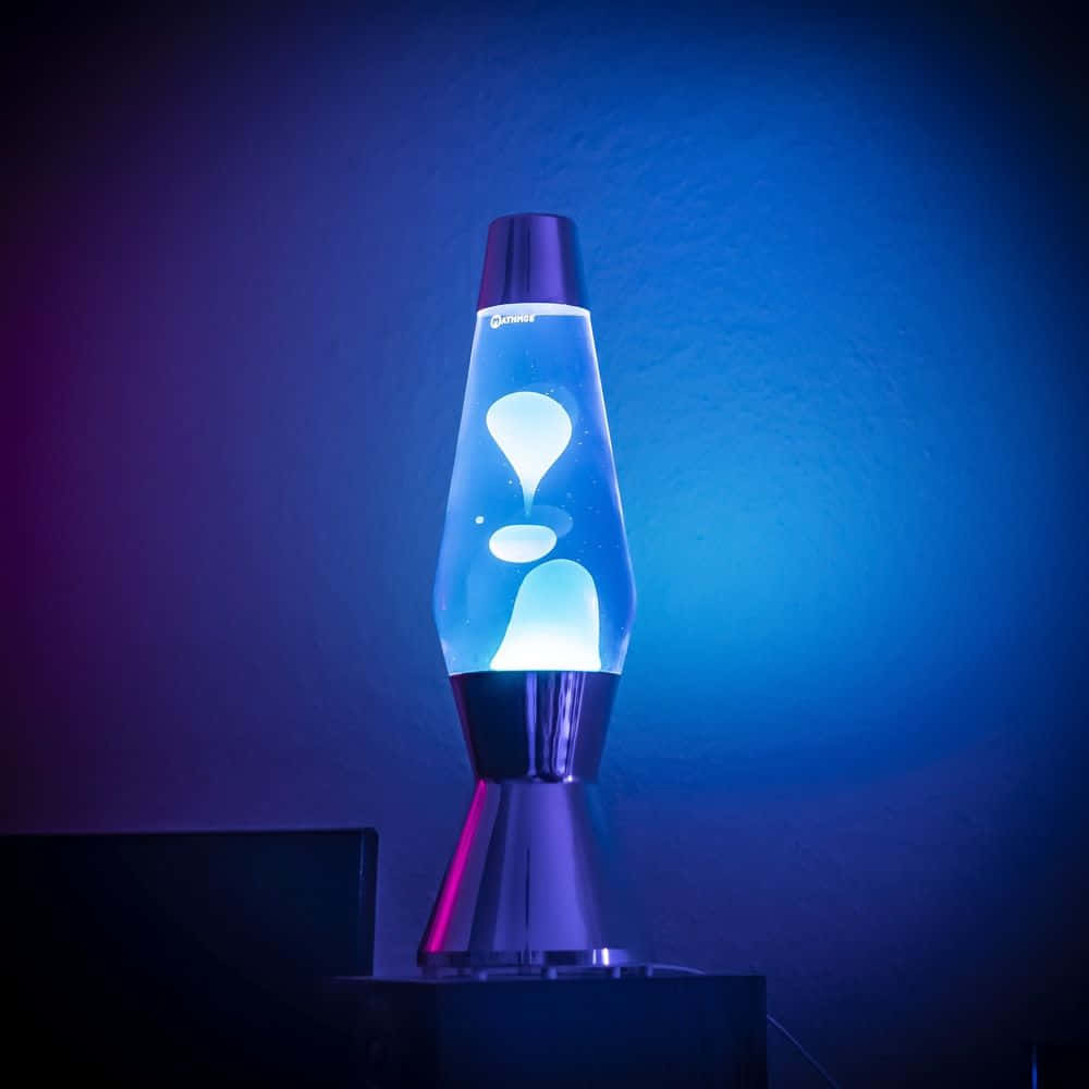 lava lamp 桌布 壁紙 — 一個發光的藍色熔岩燈，帶有白色斑點，在昏暗的房間中，映襯著漸變的紫色和藍色牆壁。