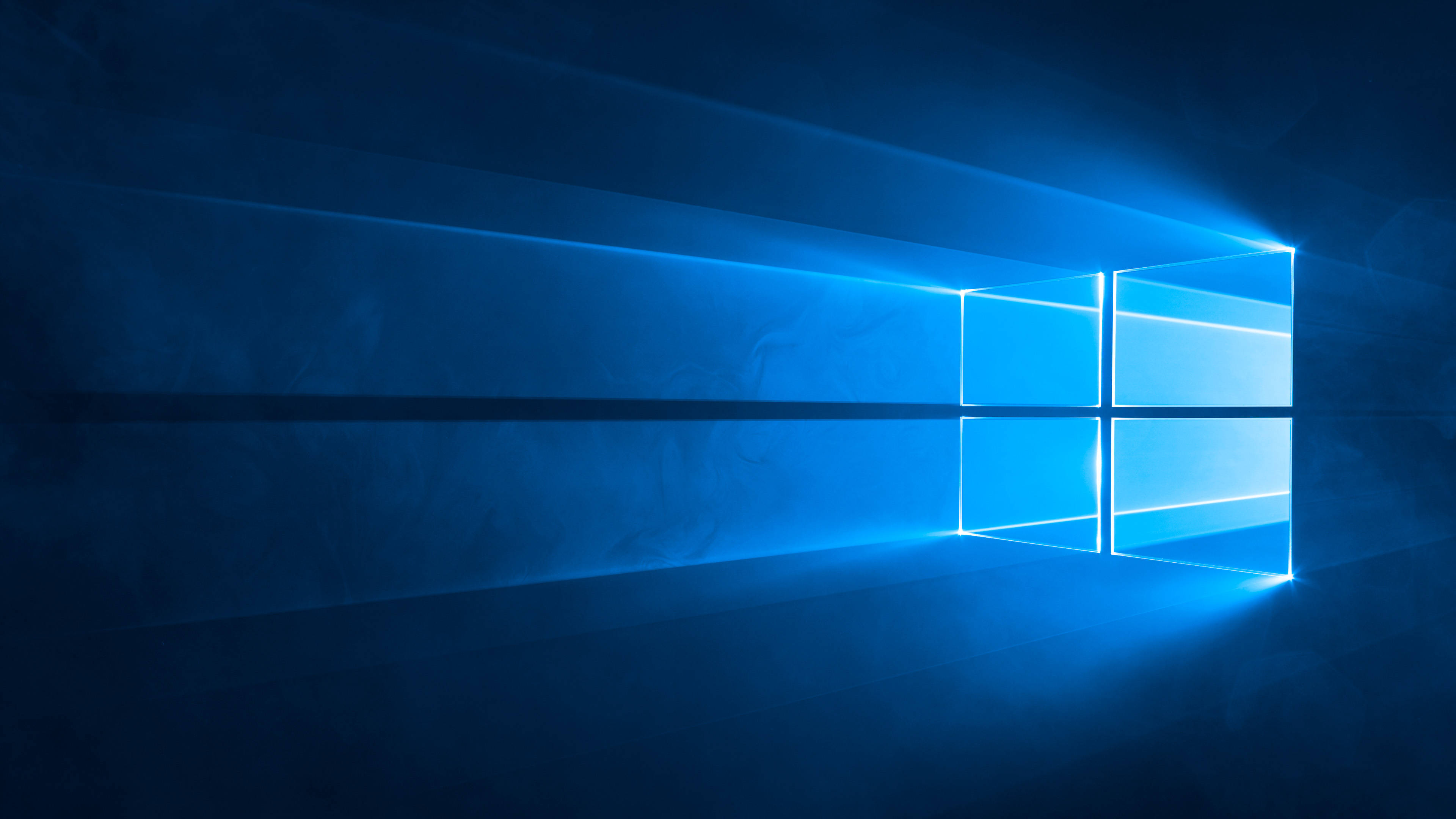 Windows Computer 桌布 壁紙 — 一個發光的藍色窗戶標誌在帶有鏡頭光暈效果的深色紋理背景上散發光芒。