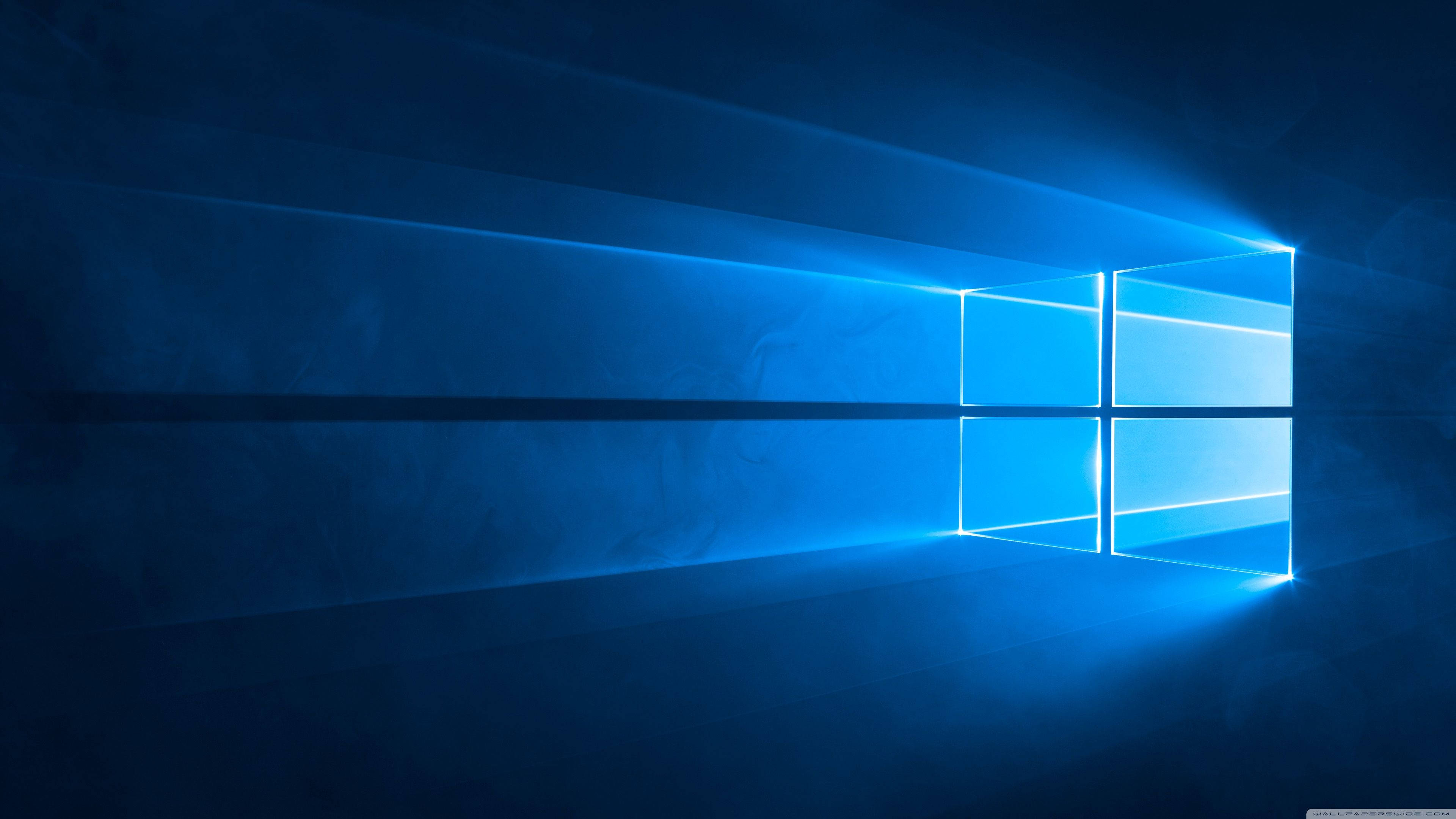 Windows 10 高畫質 桌布 壁紙 — 一個發光的藍色窗戶標誌在黑暗的抽象空間中散發出帶有光線條紋的光芒。