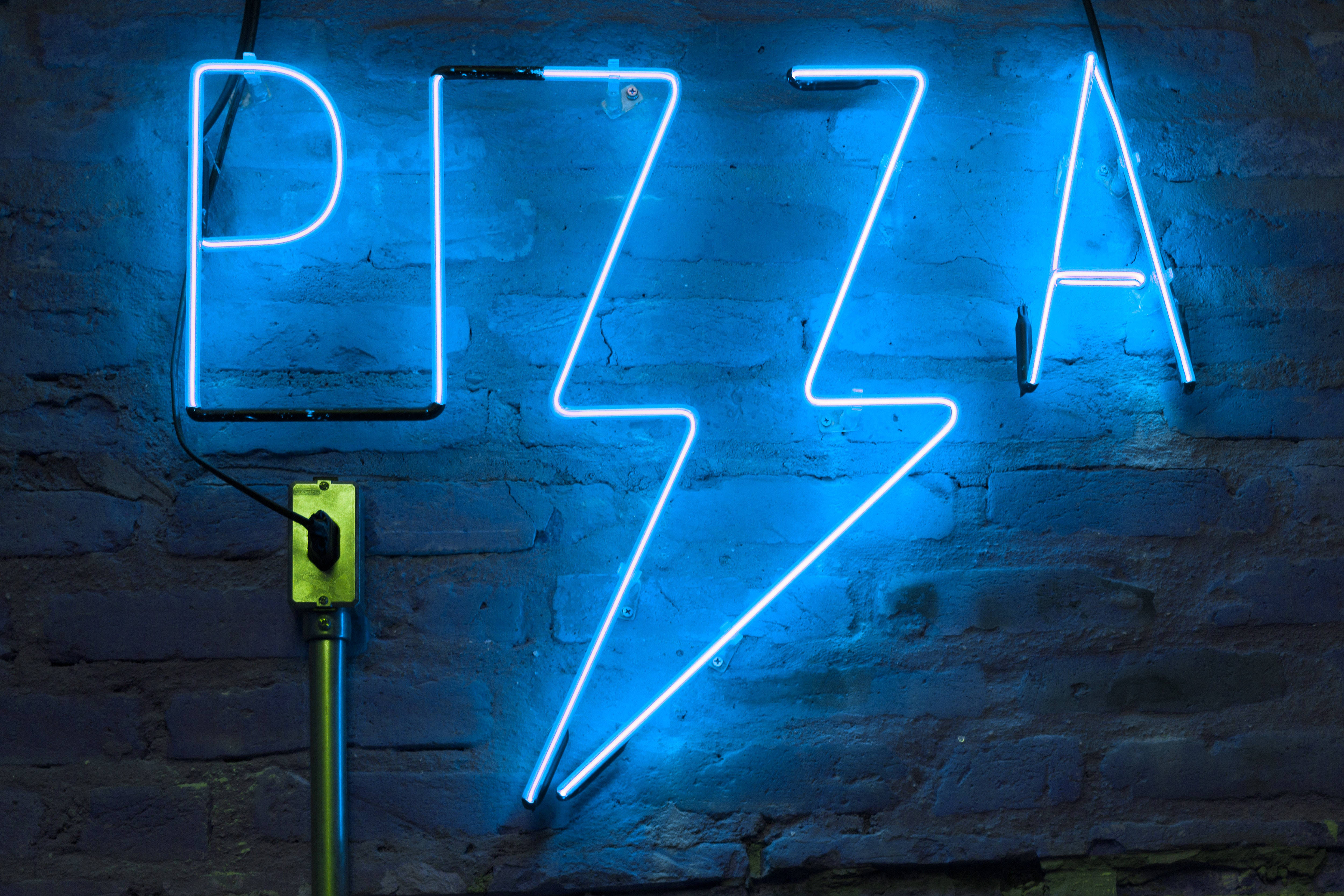 neon sign 桌布 壁紙 — 一個發光的藍色霓虹燈招牌，拼出 'PIZZA'，其中 'I' 被閃電取代，背景是深色磚牆。