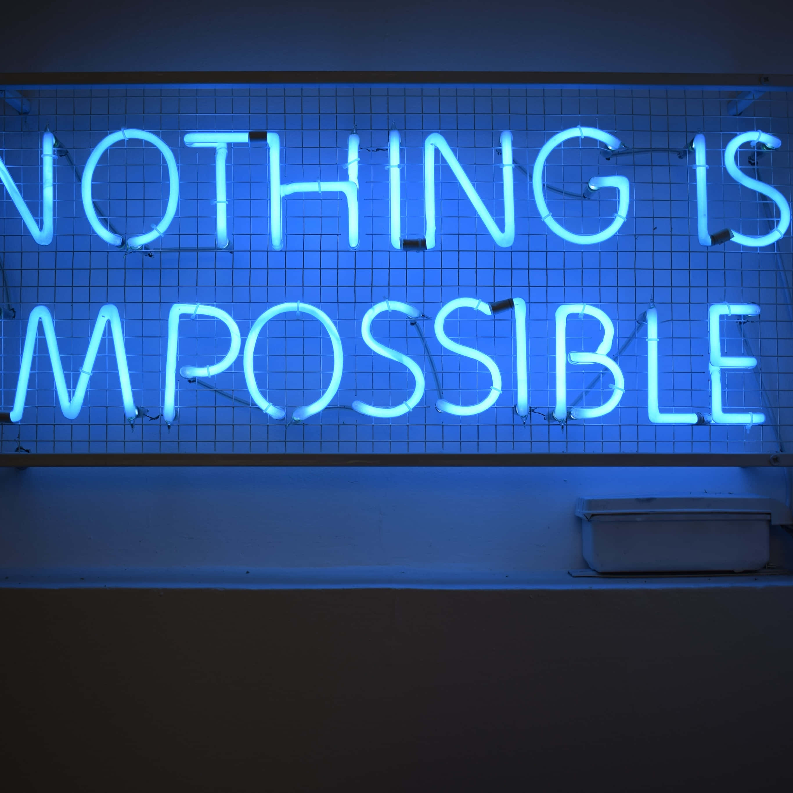 Blue Led 桌布 壁紙 — 一個發光的藍色霓虹燈牌，上面寫著 'NOTHING IS IMPOSSIBLE'，安裝在黑暗牆壁上的網格上。
