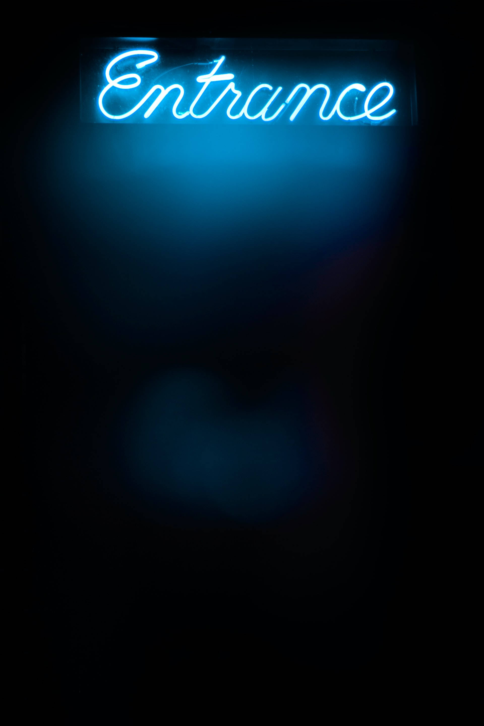 Neon Lights Aesthetic 桌布 壁紙 — 一個發光的藍色霓虹燈牌，上面寫著 'Entrance'，在漆黑的背景上投射出柔和的光線。