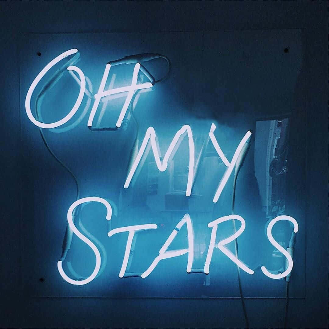 霓虹美學 桌布 壁紙 — 一個發光的藍色霓虹燈牌，上面寫著 'OH MY STARS'，掛在昏暗房間的深色牆壁上。
