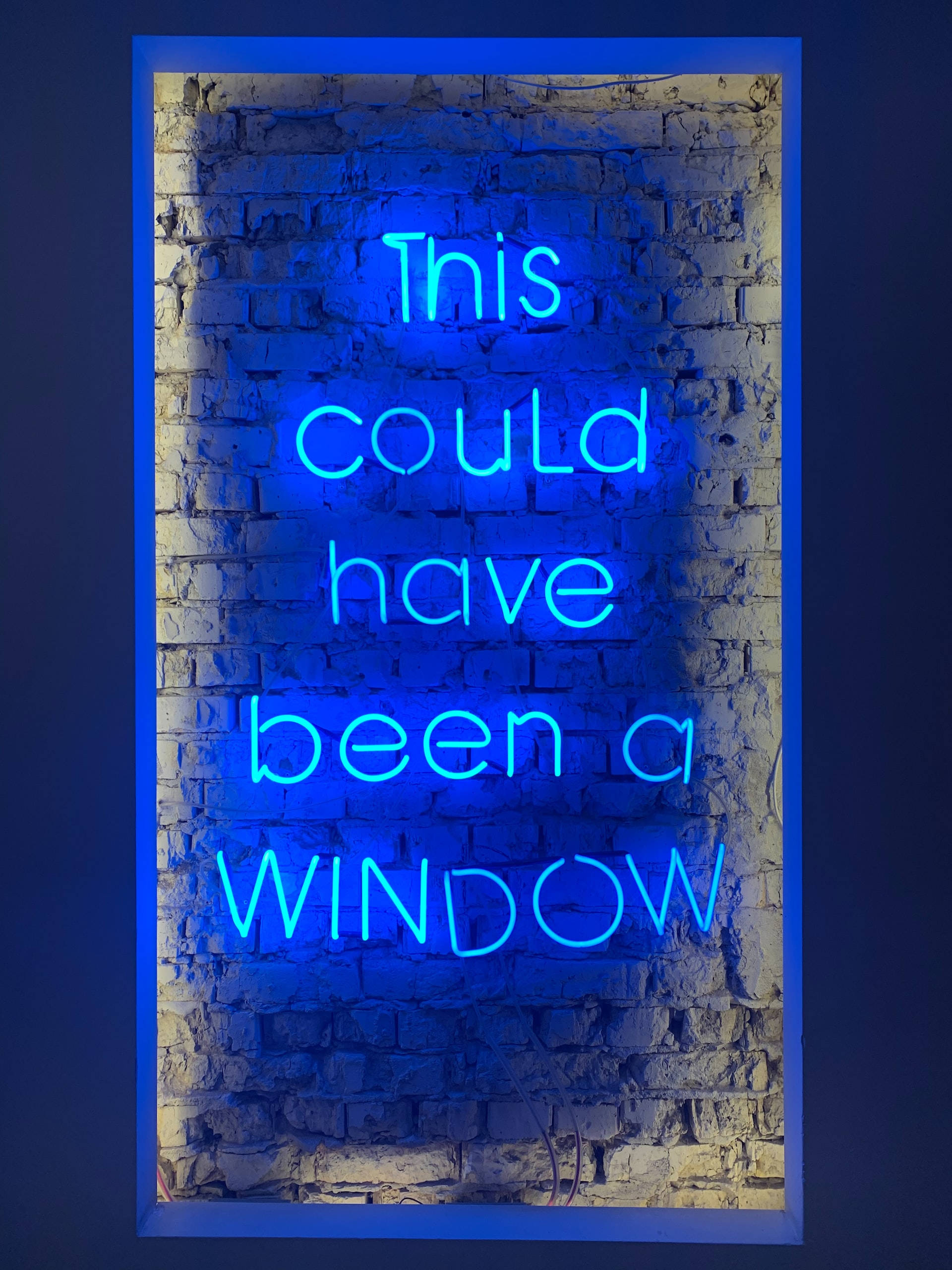 搞笑 桌布 壁紙 — 一個發光的藍色霓虹燈牌，上面寫著 'This could have been a WINDOW'，安裝在風化的磚牆上。