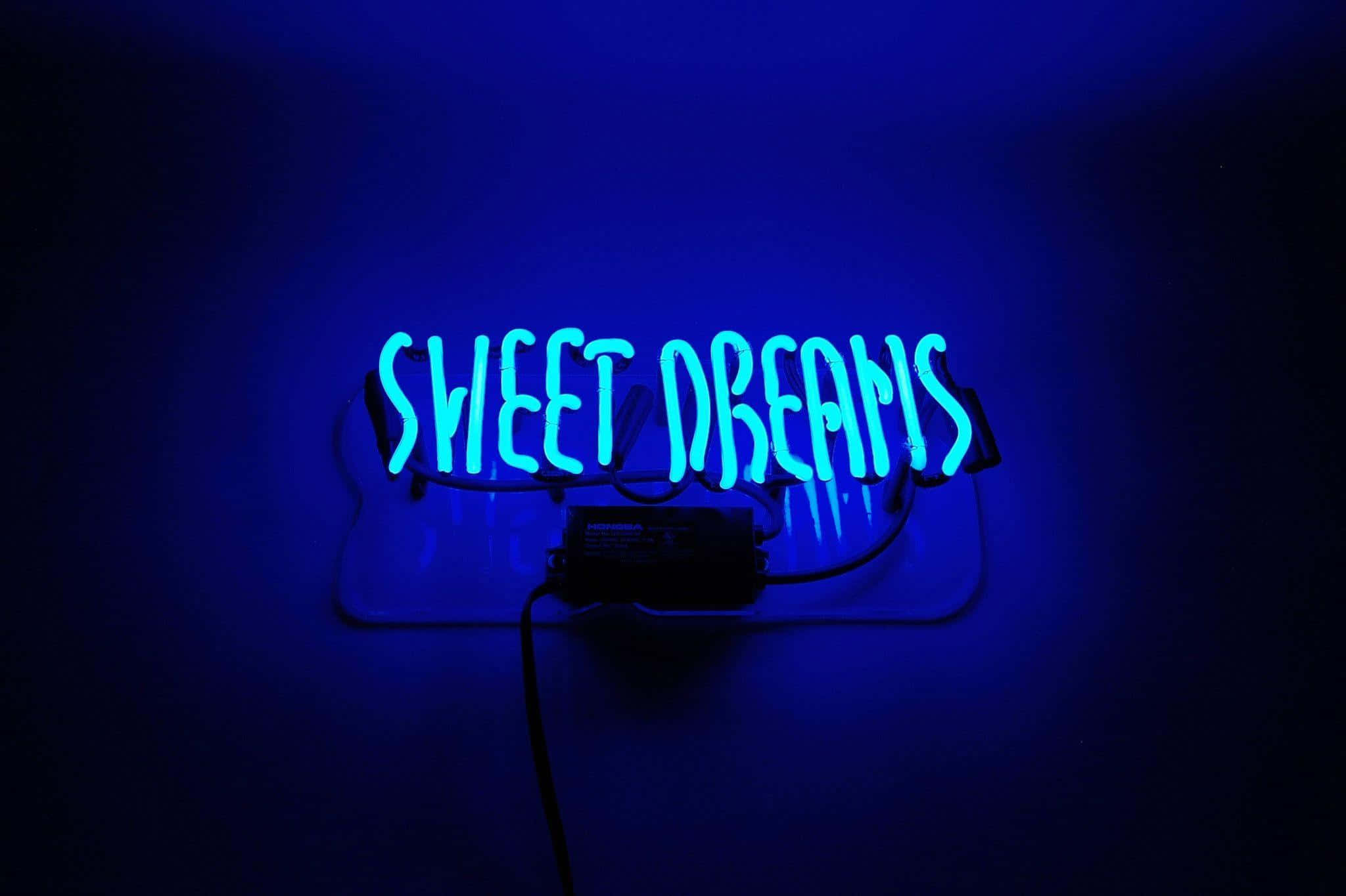 美學 桌布 壁紙 — 一個發光的藍色霓虹燈牌，上面寫著 sweet dreams，在昏暗的房間中向深色牆壁投射出柔和的光線。