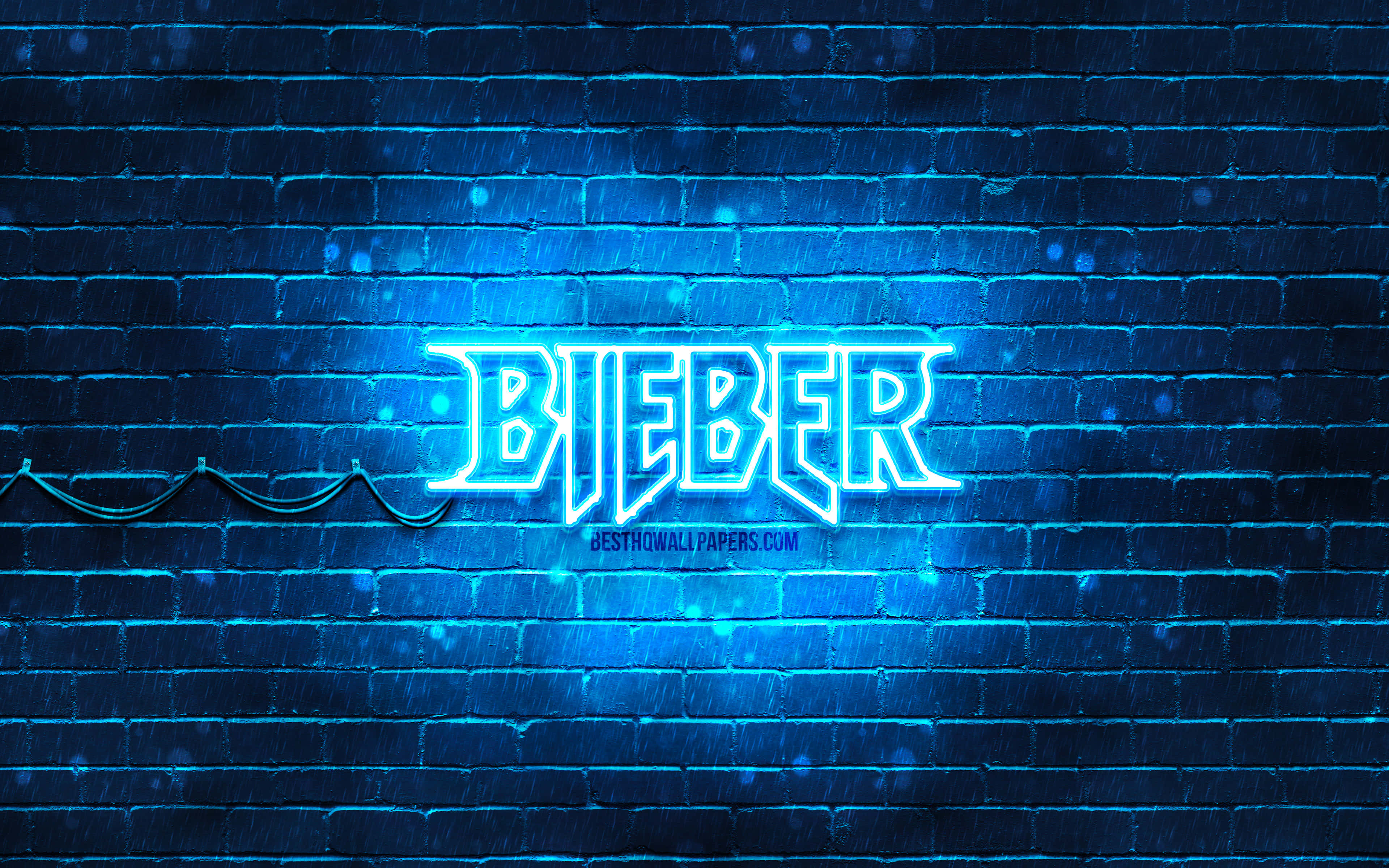 Justin Bieber 2021 桌布 壁紙 — 一個發光的藍色霓虹燈牌，上面拼寫著「BIEBER」，照亮了夜雨中濕漉漉的磚牆。