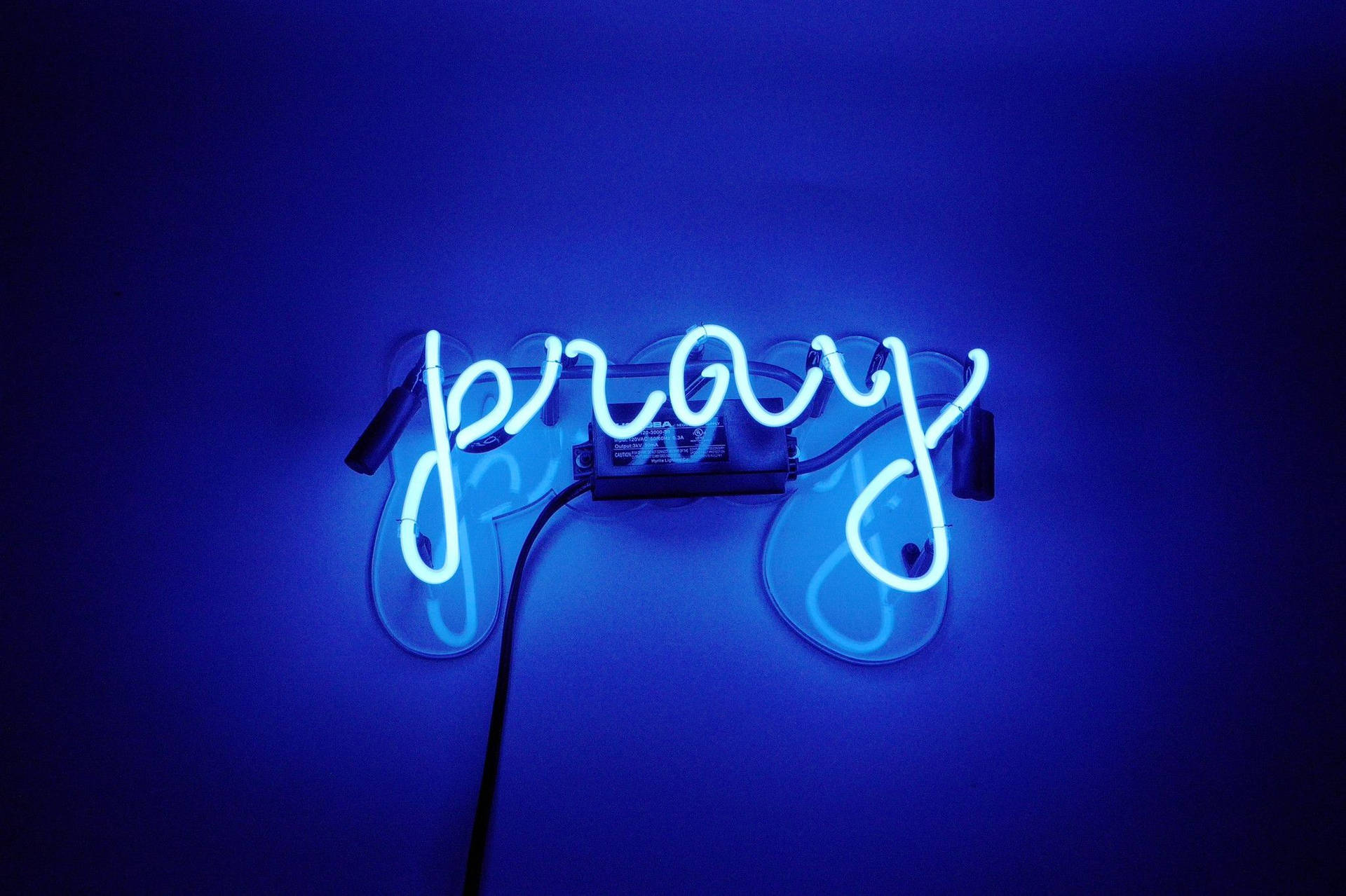 藍色霓虹燈牌，上面有「pray」字樣在暗牆上發光。 — 美學語錄動圖 壁紙