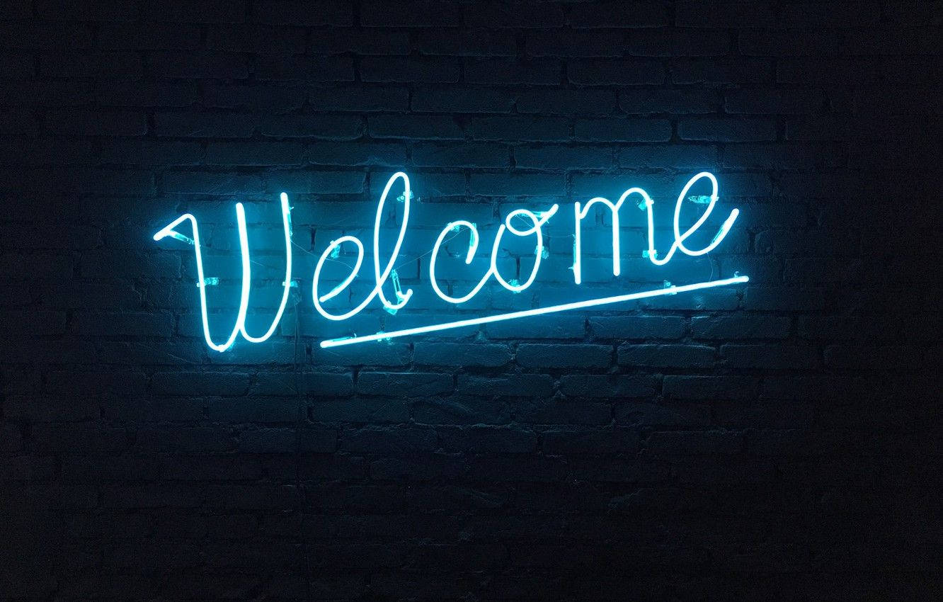 Welcome 桌布 壁紙 — 一個發光的藍色霓虹燈牌，以草書拼出 'Welcome'，掛在昏暗空間中的深色磚牆上。