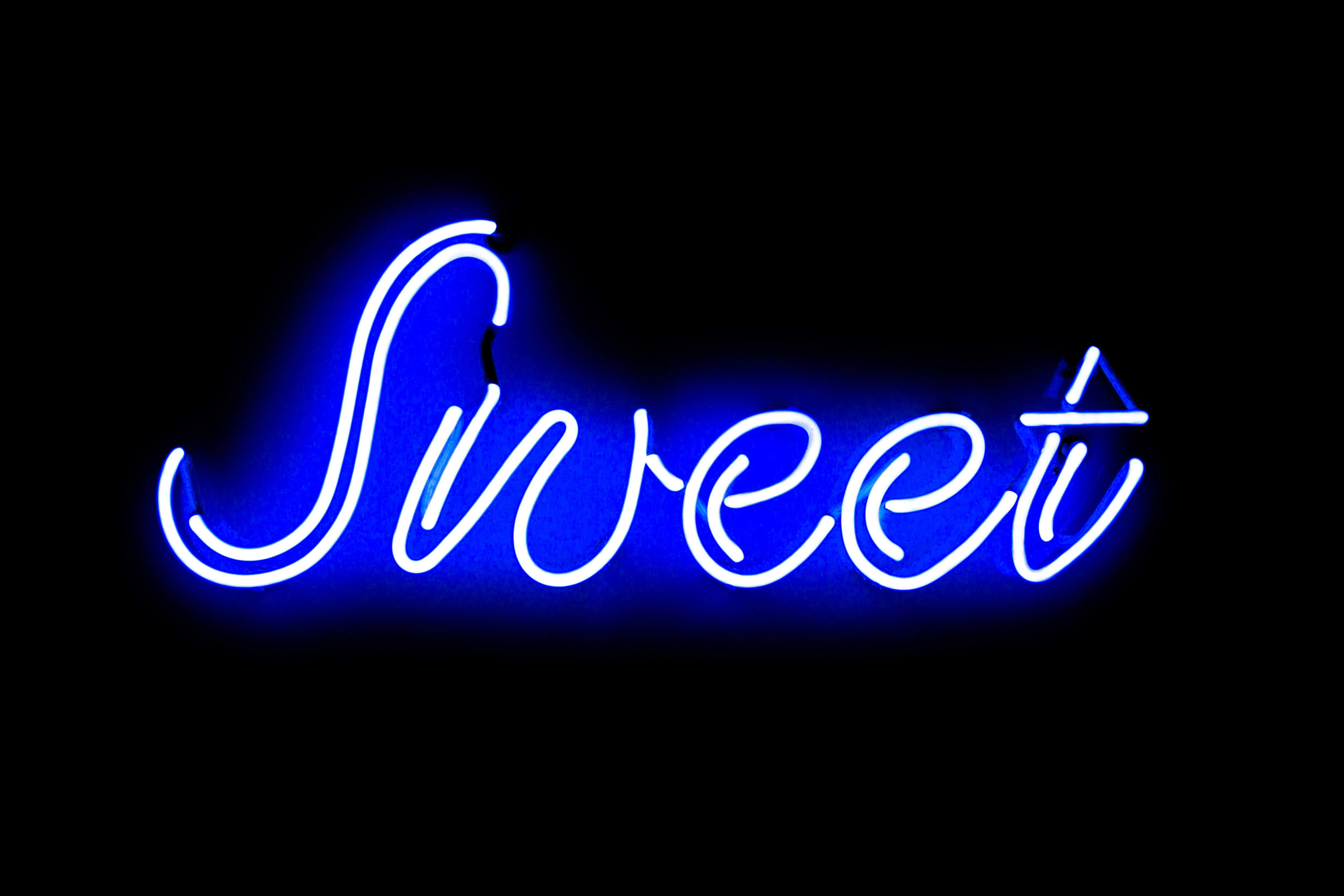 Neon Quotes 桌布 壁紙 — 一個發光的藍色霓虹燈牌，在漆黑背景上用草書拼出「Sweet」。