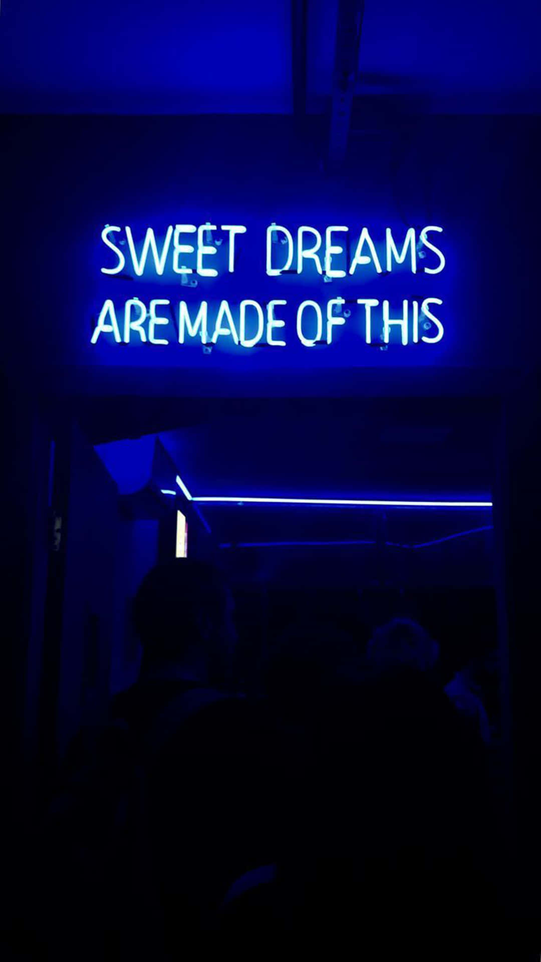 藍色美學 桌布 壁紙 — 一個發光的藍色霓虹燈牌寫著「sweet dreams are made of this」，在一個黑暗的房間裡，下方有剪影人物。