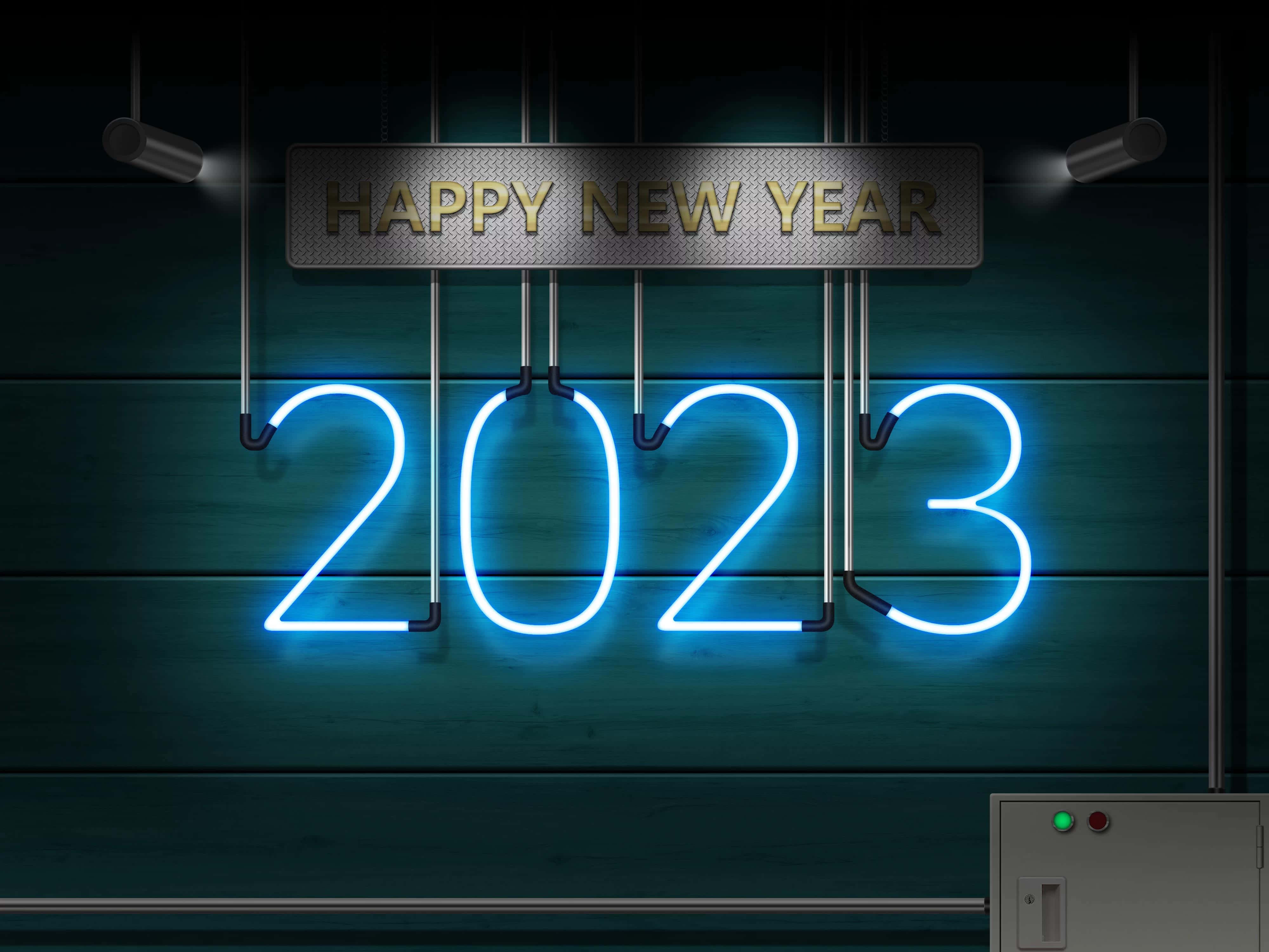 Neon Light 桌布 壁紙 — 一個發光的藍色霓虹燈牌顯示2023，掛在深色木牆上，聚光燈下，上方有「HAPPY NEW YEAR」牌匾。