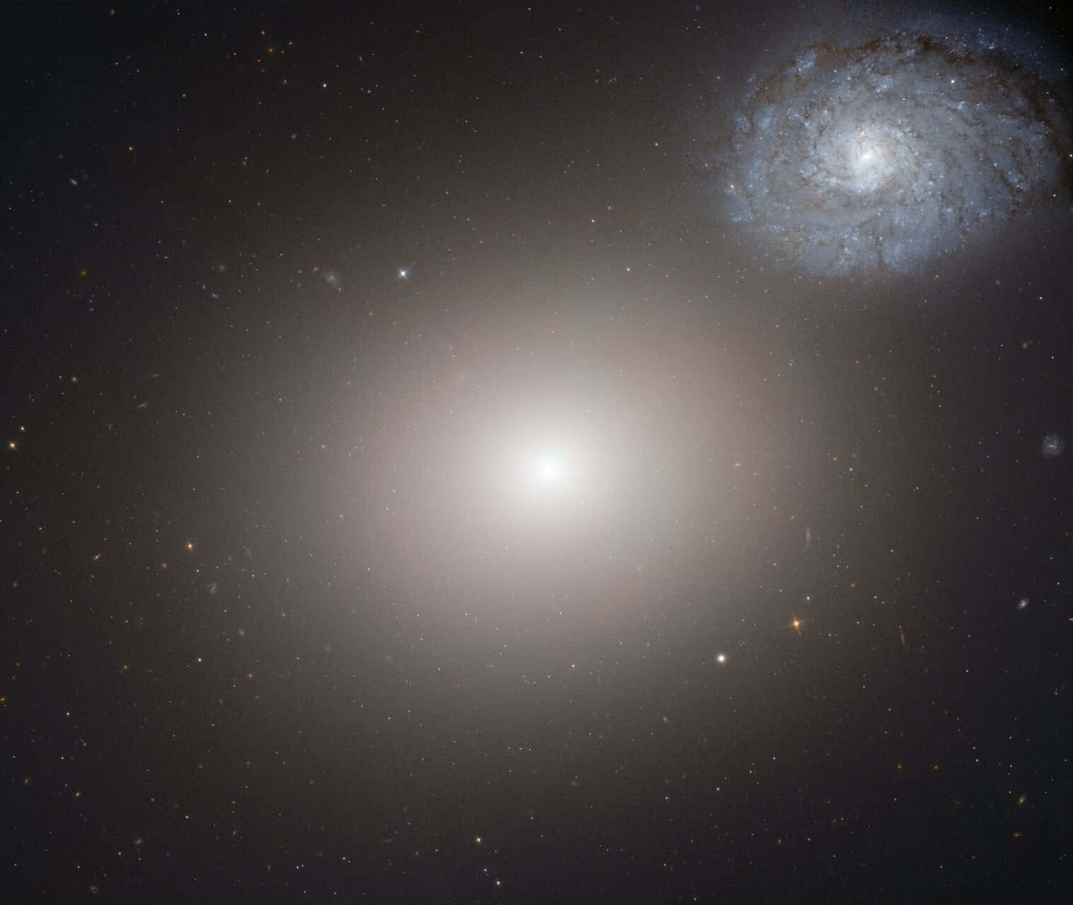 Elliptical Galaxy 桌布 壁紙 — 一個發光的螺旋星系主宰著宇宙場景，其旋轉的臂和無數的星星在黑暗的虛空中閃耀。