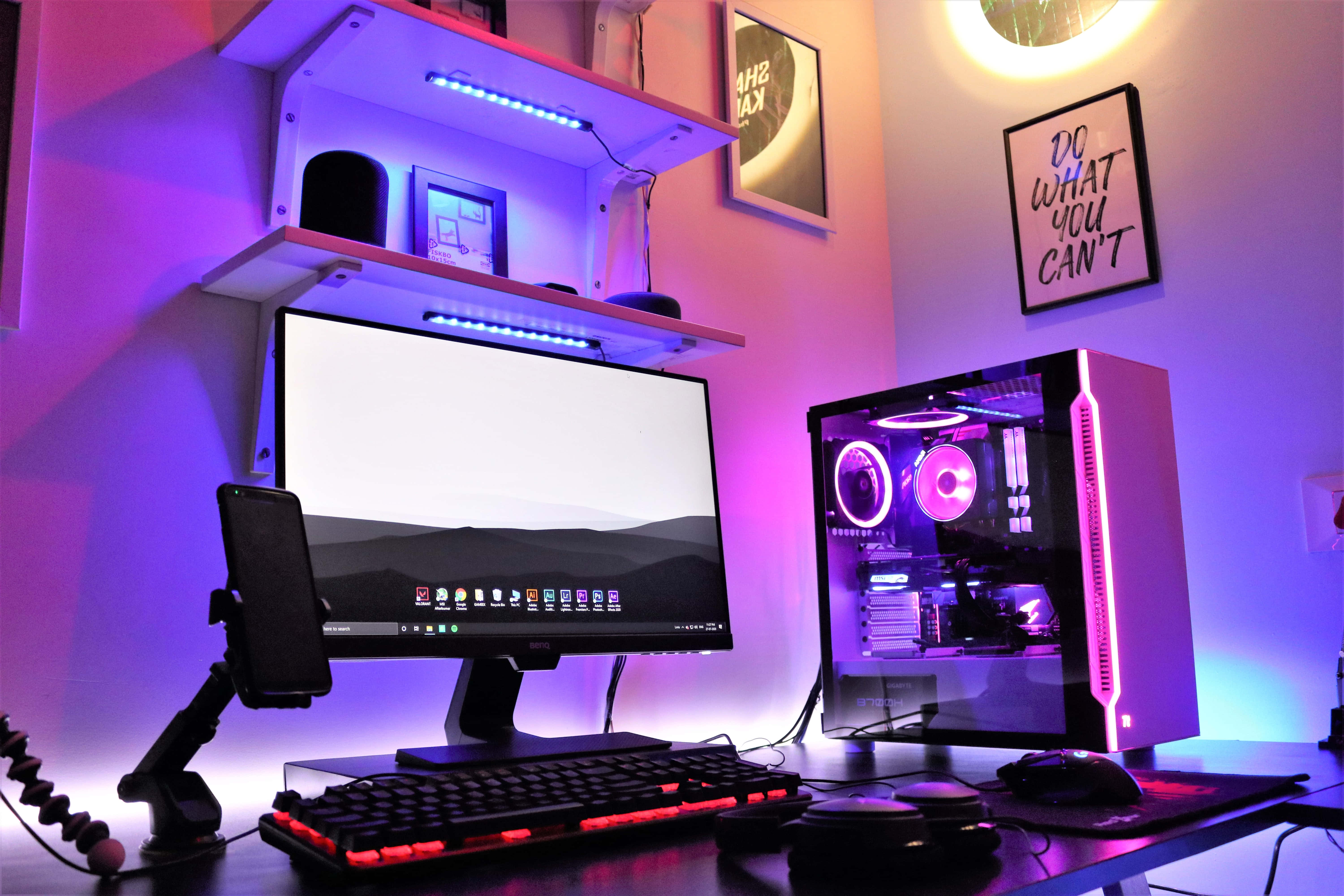 Gaming Pc 桌布 壁紙 — 一個發光的遊戲設置，配有紫色照明的PC機箱和紅色背光鍵盤，在環境光下。