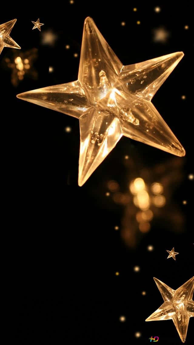 Christmas Star 桌布 壁紙 — 一個發光的金色星星裝飾漂浮在黑暗背景上，帶有散景燈光和散落的星星。