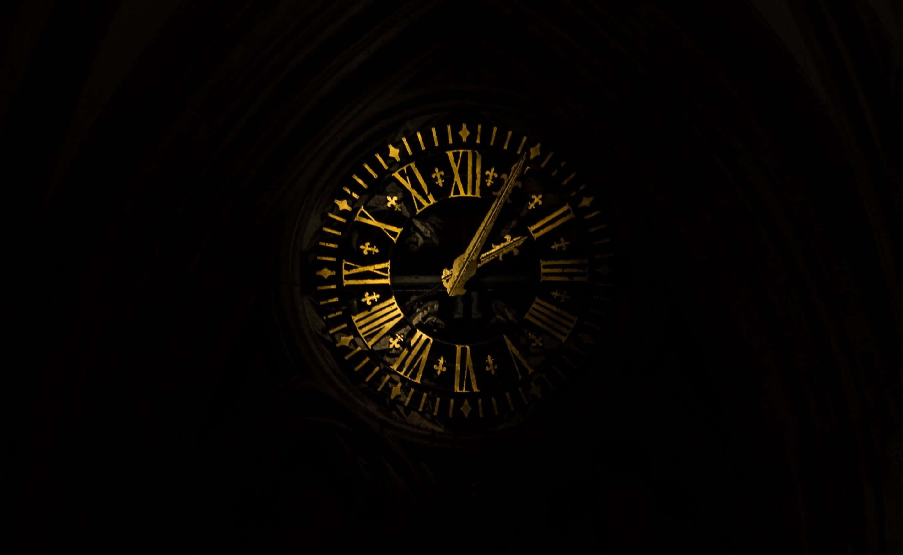Clock 桌布 壁紙 — 一個發光的金色時鐘，帶有羅馬數字和百合花飾符號，照亮了哥德式大教堂內部的黑暗。