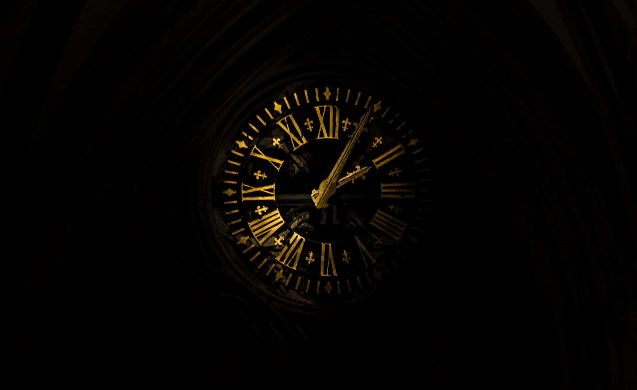 Clocks 桌布 壁紙 — 一個發光的金色時鐘，帶有羅馬數字和百合花飾，照亮了黑暗的哥德式拱門。