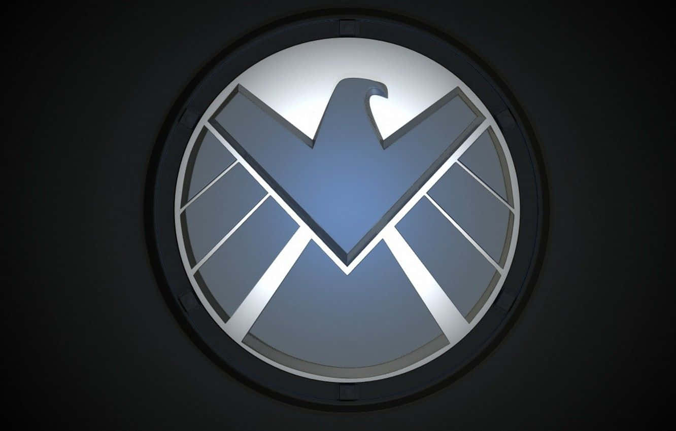 Marvel Logo 桌布 壁紙 — 一個發光的銀色S.H.I.E.L.D.標誌，中央有鷹徽章，位於圓形框架內，背景為深色。