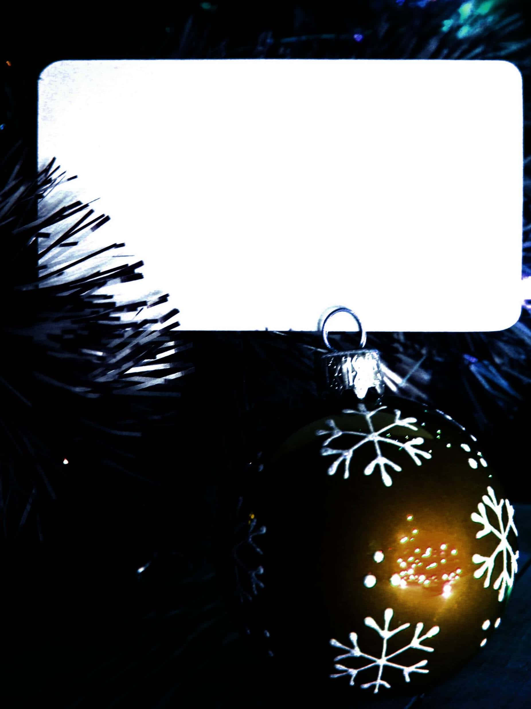 Christmas Invitation 桌布 壁紙 — 一個發光的雪花裝飾品掛在深色樹枝上，上方有一個明亮的白色標籤。