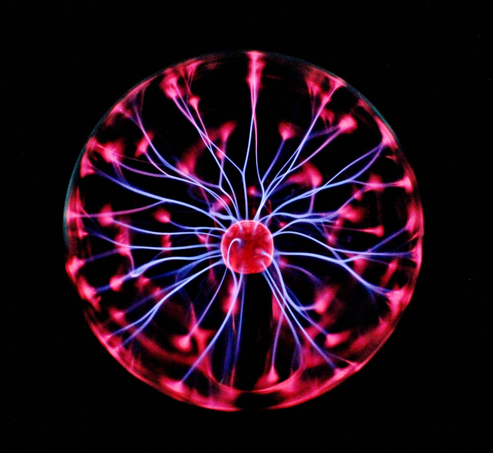 dark neon iPhone 桌布 壁紙 — 一個發光的電漿球，帶有鮮豔的粉紅色和藍色電觸手，從中心核心向黑色背景輻射。