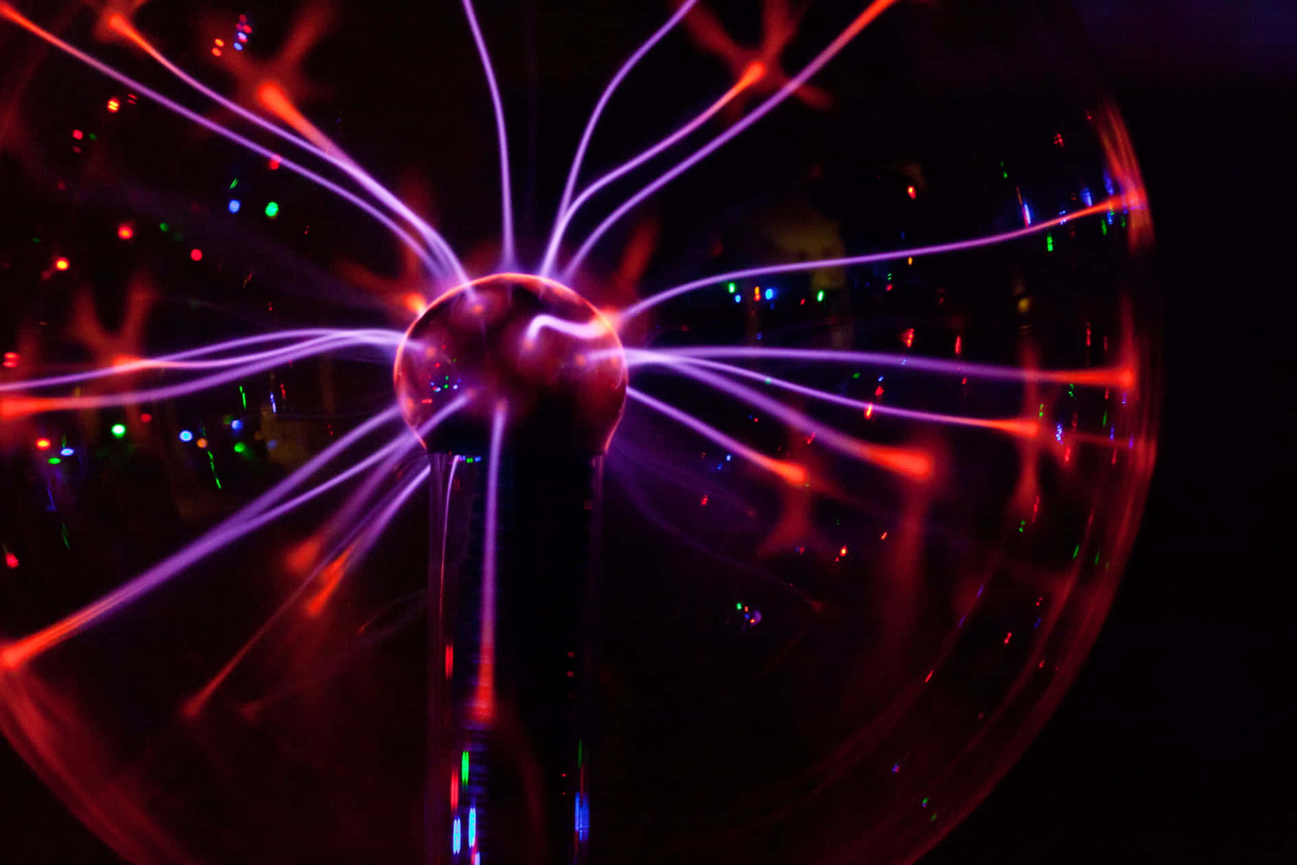 Trippy Neon Lights 桌布 壁紙 — 一個發光的電漿球在黑暗背景上散發出充滿活力的紫色和紅色電觸手，並伴有散落的彩色燈光。