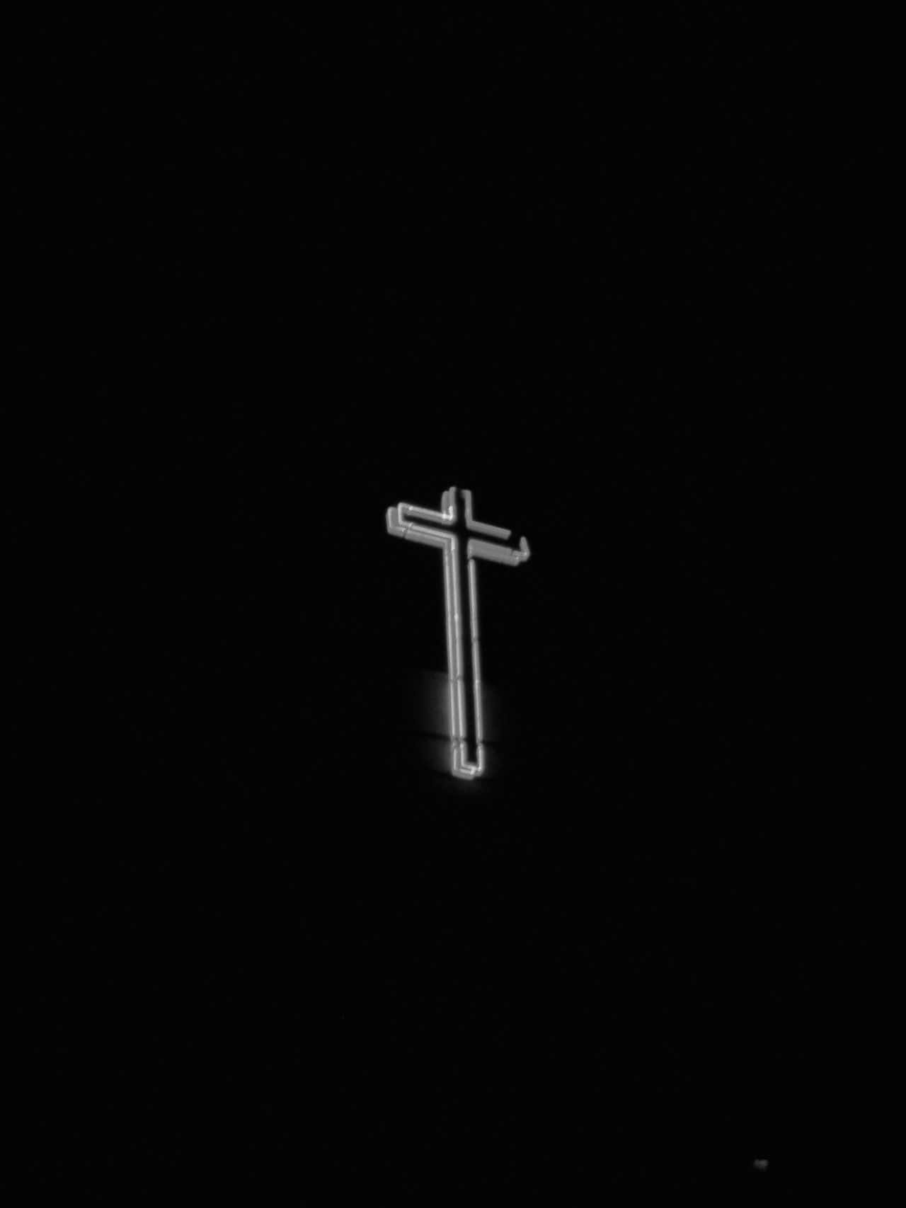 Cute Cross 桌布 壁紙 — 一個發光的霓虹十字架獨自矗立在漆黑的夜空下，在黑暗中投射出柔和的光芒。