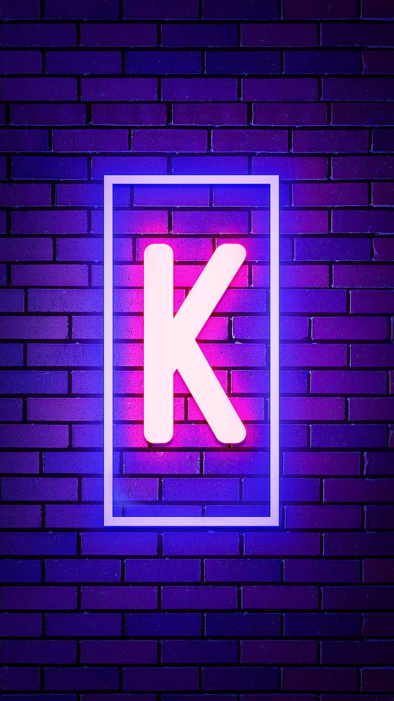 霓虹字母K在深色磚牆上發出粉紅色和藍色光芒。 — 字母K動圖 壁紙