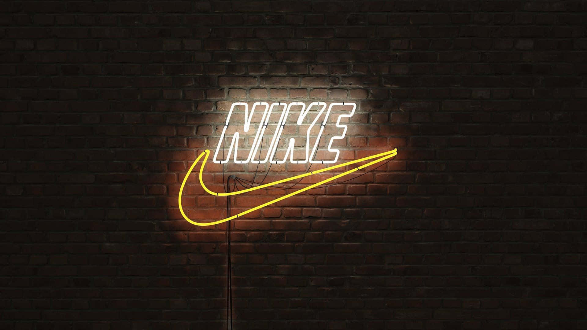 White Neon 桌布 壁紙 — 一個發光的霓虹燈Nike標誌，白色字體和黃色勾號照亮了陰暗城市環境中的深色磚牆。