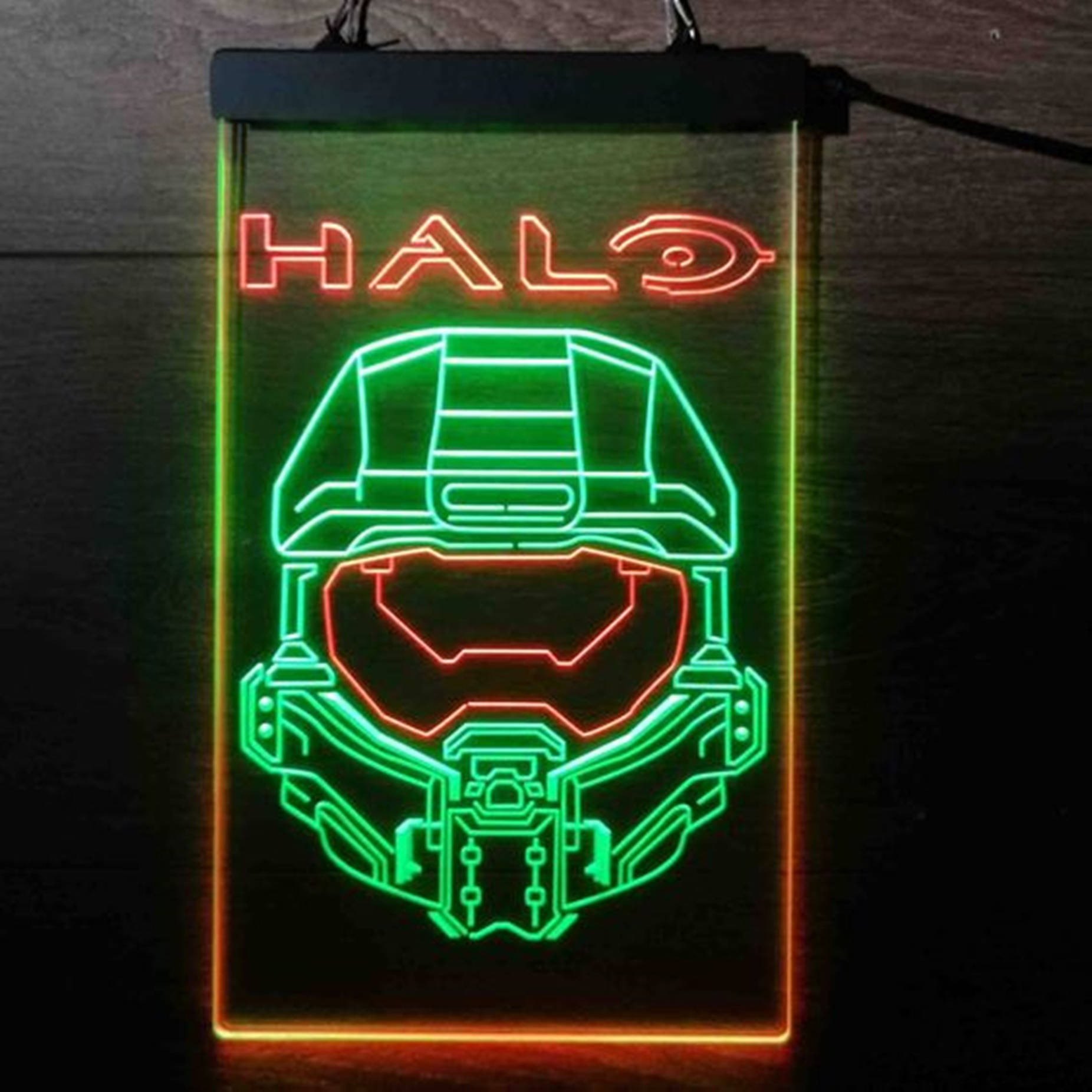 Halo 桌布 壁紙 — 一個發光的霓虹燈牌在深色木牆上展示Halo標誌和Master Chief頭盔，呈現鮮豔的綠色和紅色。
