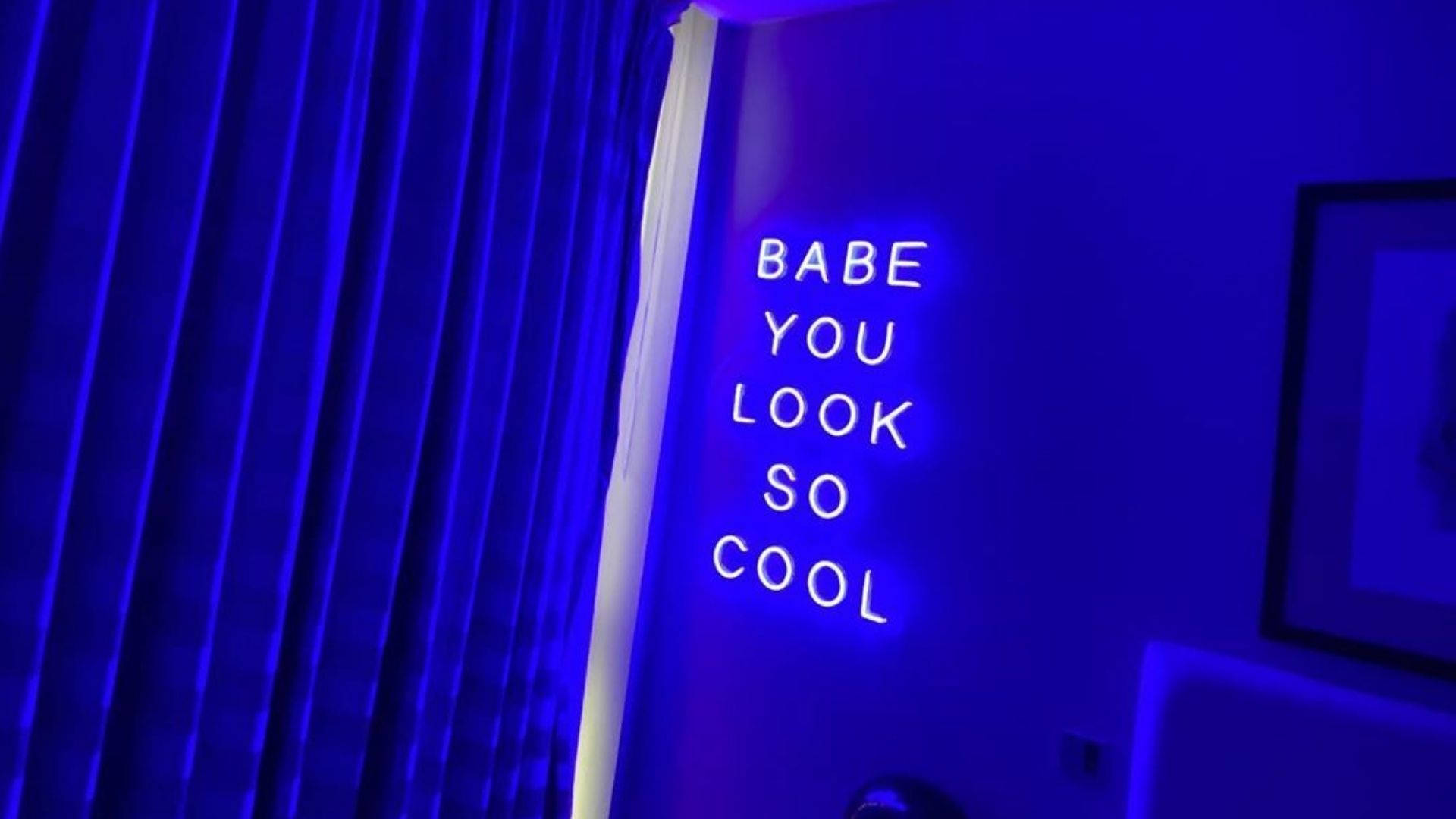 霓虹藍動畫 桌布 壁紙 — 一個發光的霓虹燈牌寫著 babe you look so cool，背景是深藍色牆壁，旁邊有垂直百葉窗。