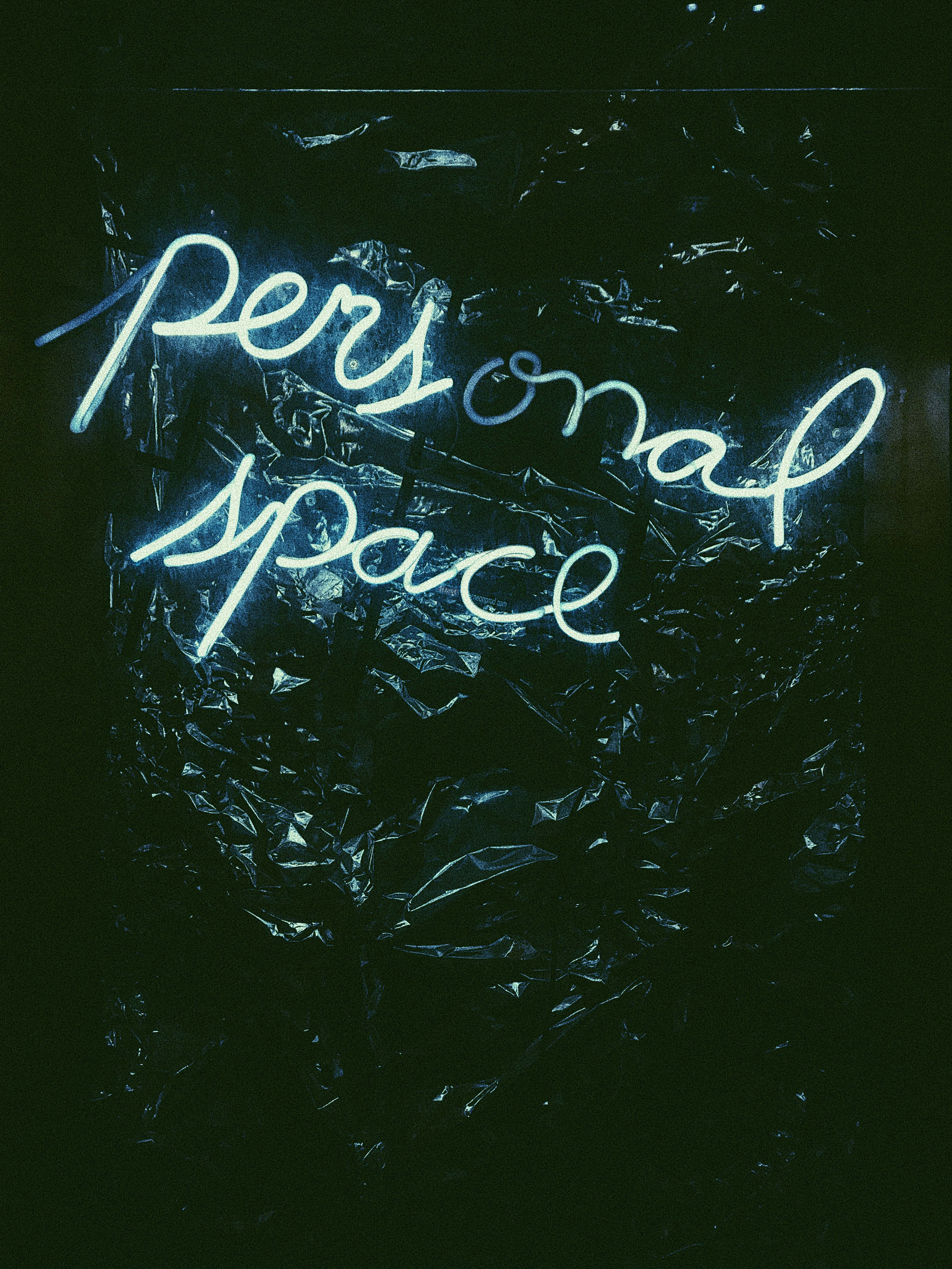 手機 桌布 壁紙 — 一個發光的霓虹燈牌寫著personal space，在黑暗背景上將冷藍光投射到皺巴巴的黑色塑膠上。