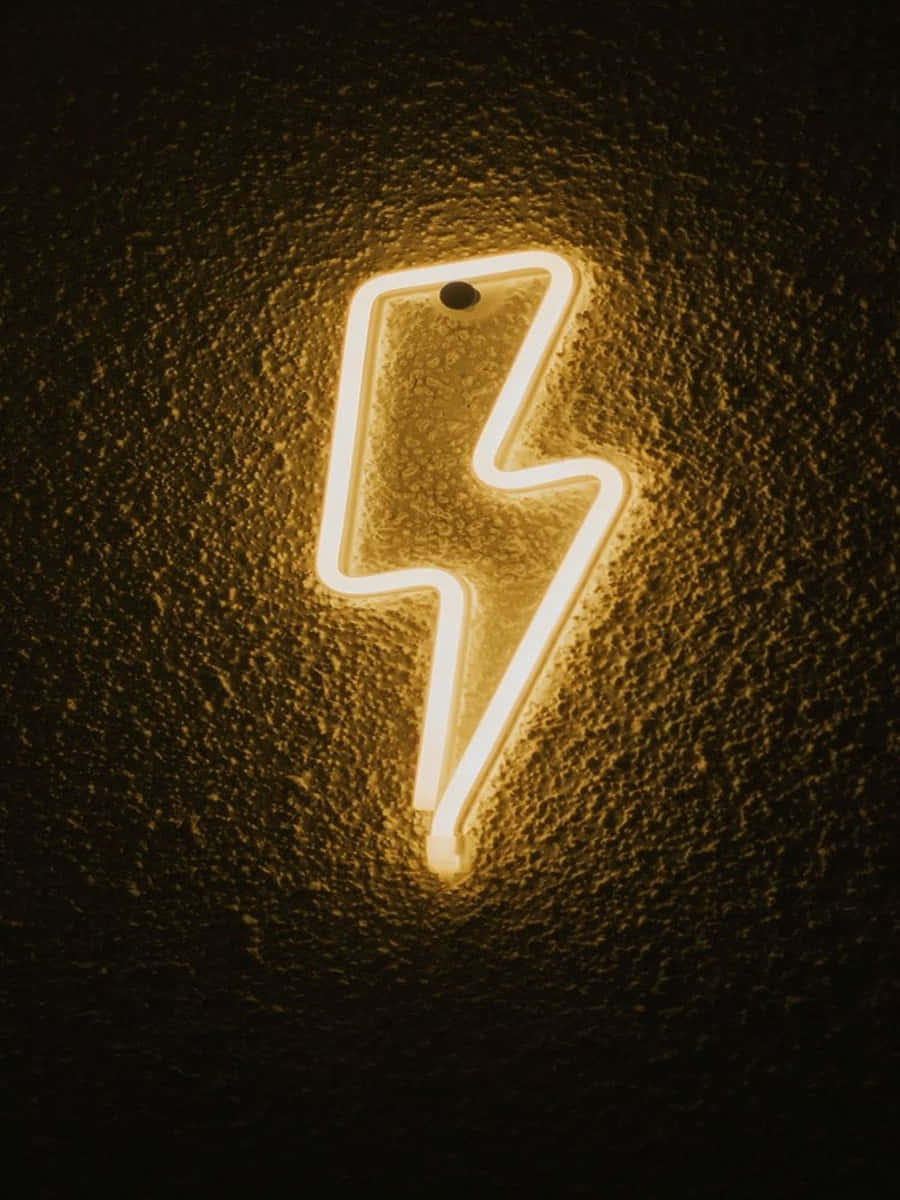 Neon Lightning 桌布 壁紙 — 一個發光的霓虹閃電標誌在深色紋理牆壁上投射出溫暖的金色光芒。