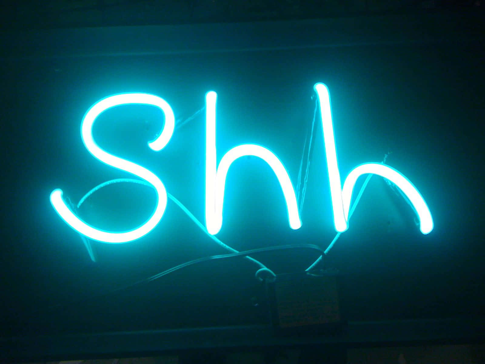 neon sign 桌布 壁紙 — 一個發光的青色霓虹燈牌，拼出「Shh」，帶有可見的電線，背景為深色。
