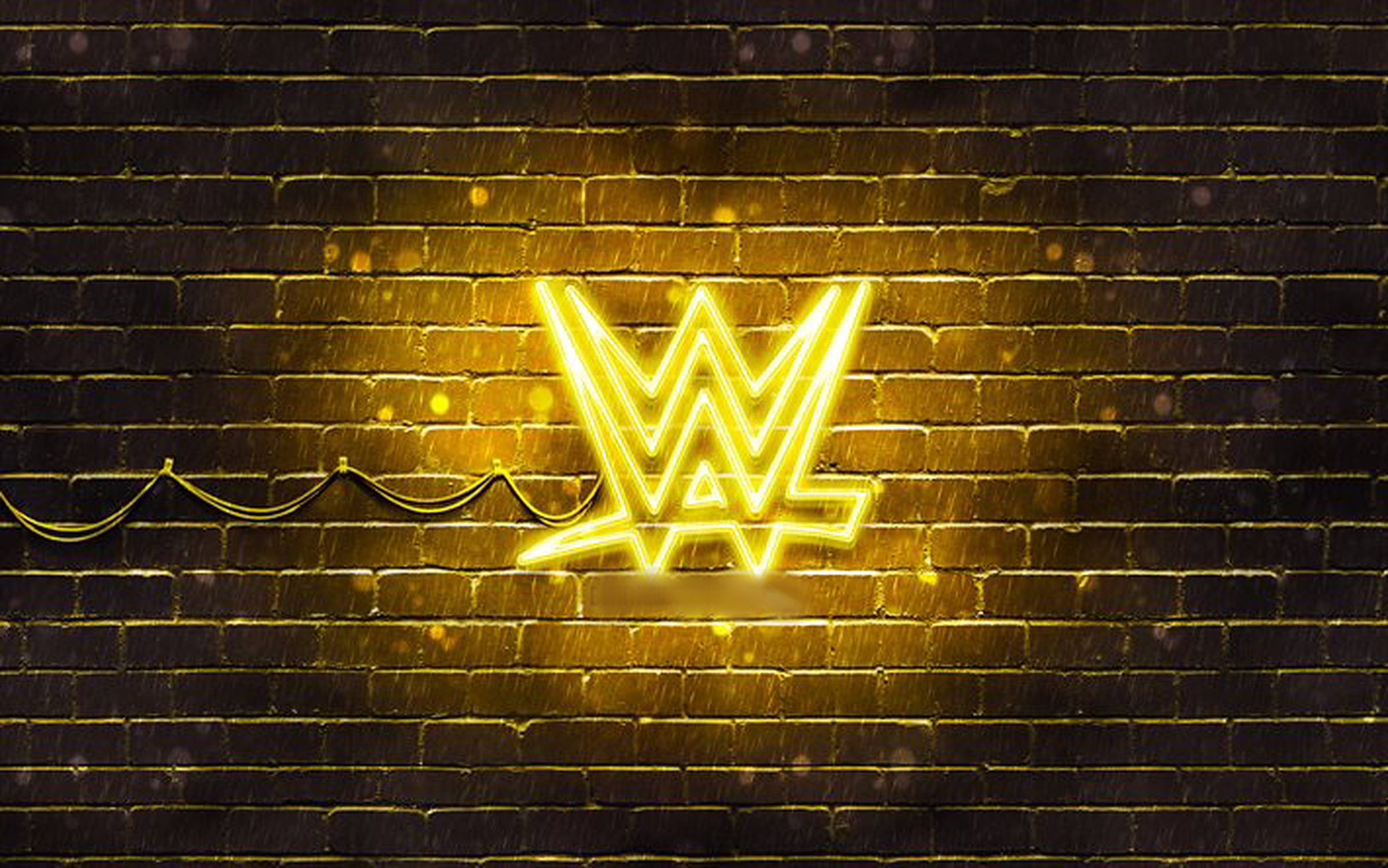 WWE 桌布 壁紙 — 一個發光的黃色WWE霓虹燈牌在夜晚照亮濕漉漉的磚牆，在雨水濕滑的表面上投射出溫暖的光線和反射。