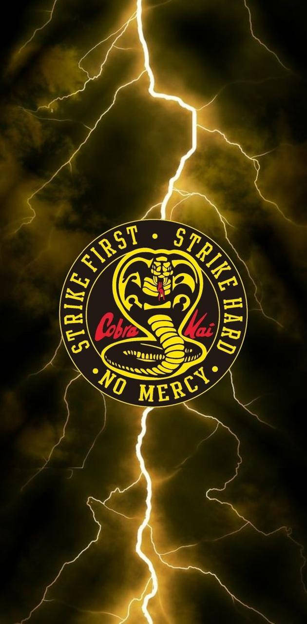 Lightning Bolt 桌布 壁紙 — 一個發光的黃色眼鏡蛇標誌，帶有「Strike First Strike Hard No Mercy」文字，居中於黑暗暴風雨的天空，伴有明亮的閃電。