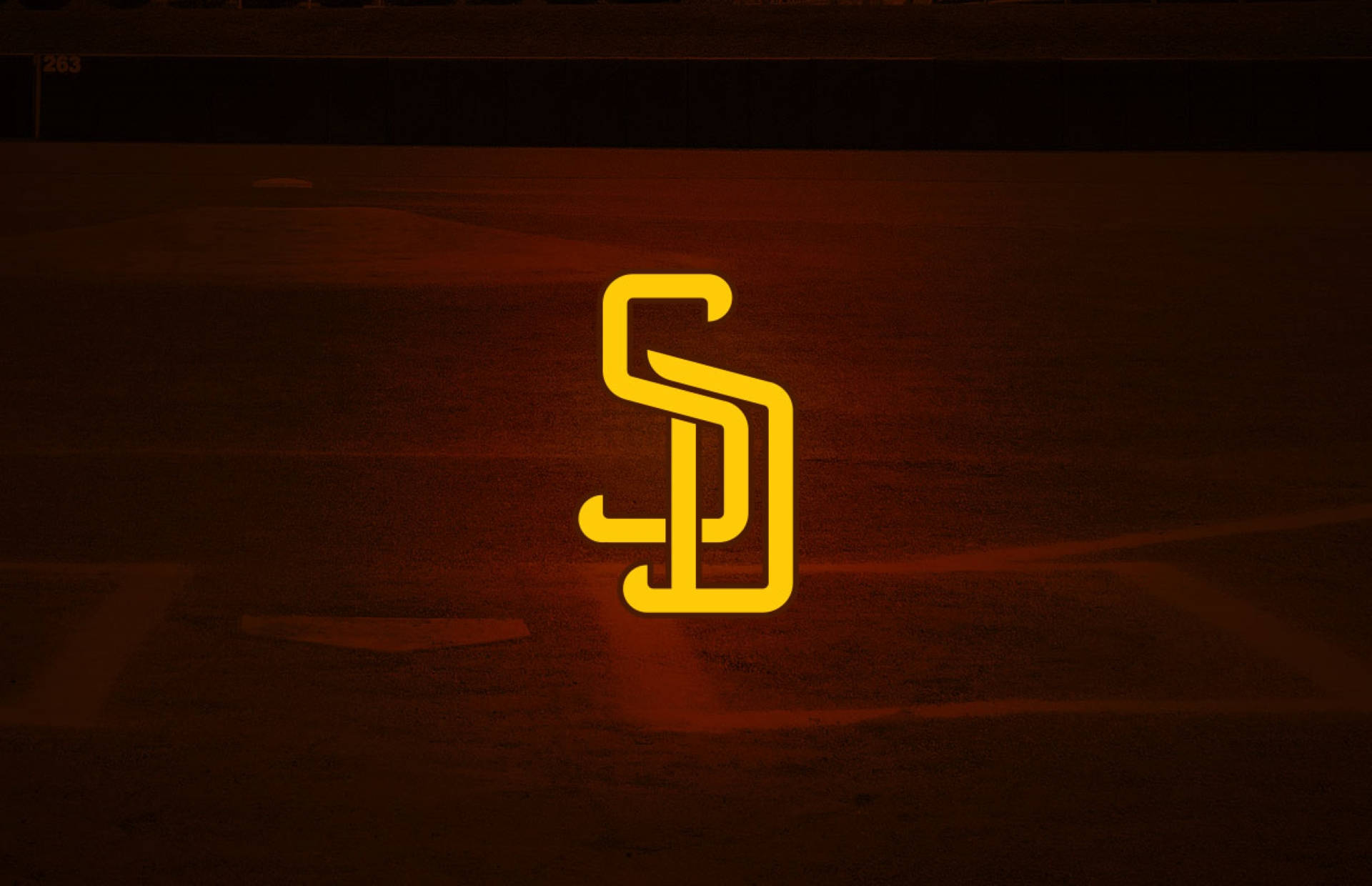 Padres 桌布 壁紙 — 一個發光的黃色聖地牙哥教士隊標誌在夜間照亮了球場燈光下的黑暗棒球場。