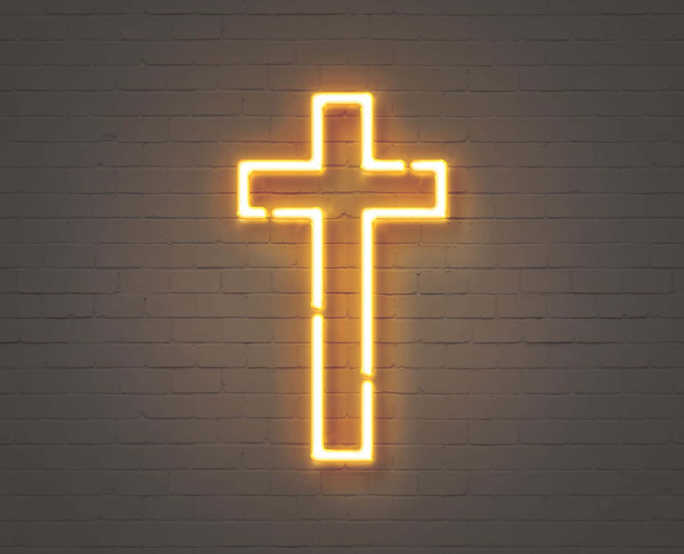 Cute Cross 桌布 壁紙 — 一個發光的黃色霓虹十字架，以柔和環境光線照亮帶紋理的白色磚牆。